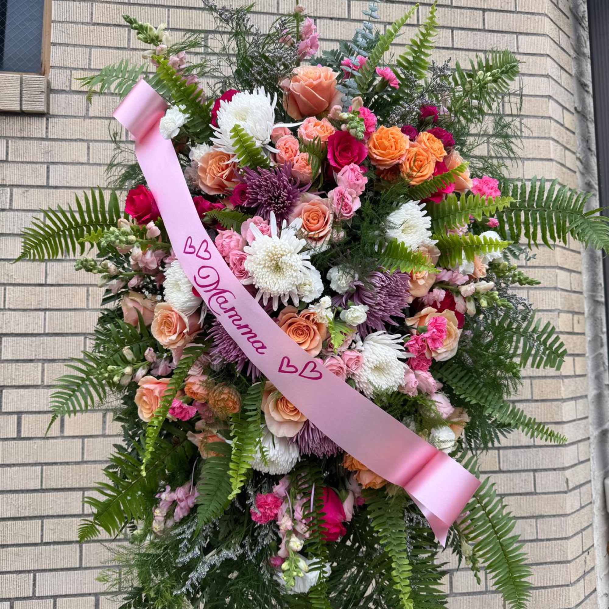 Large pink and peach floral standing spray with a pink ribbon