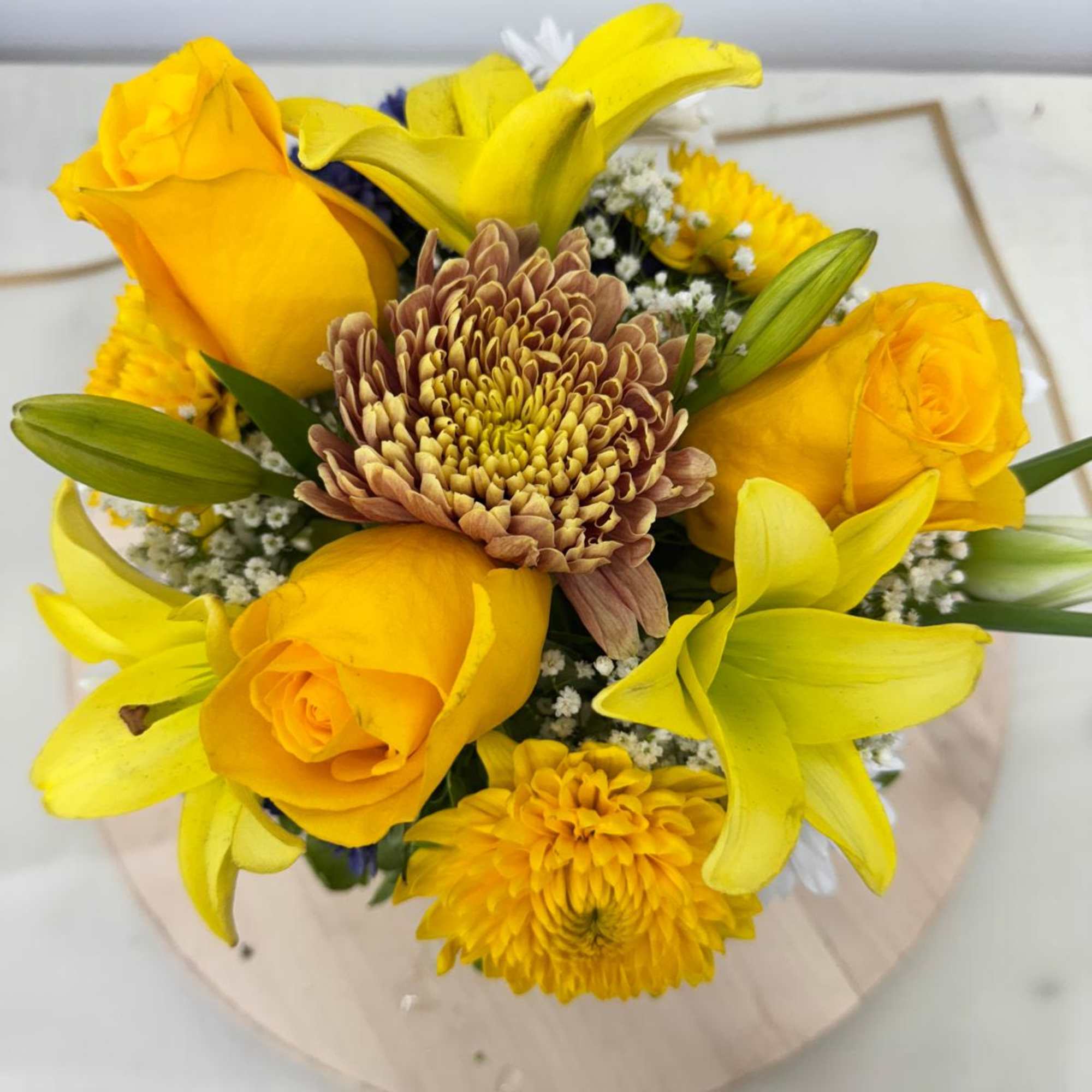 Yellow roses and lilies with a central chrysanthemum bouquet