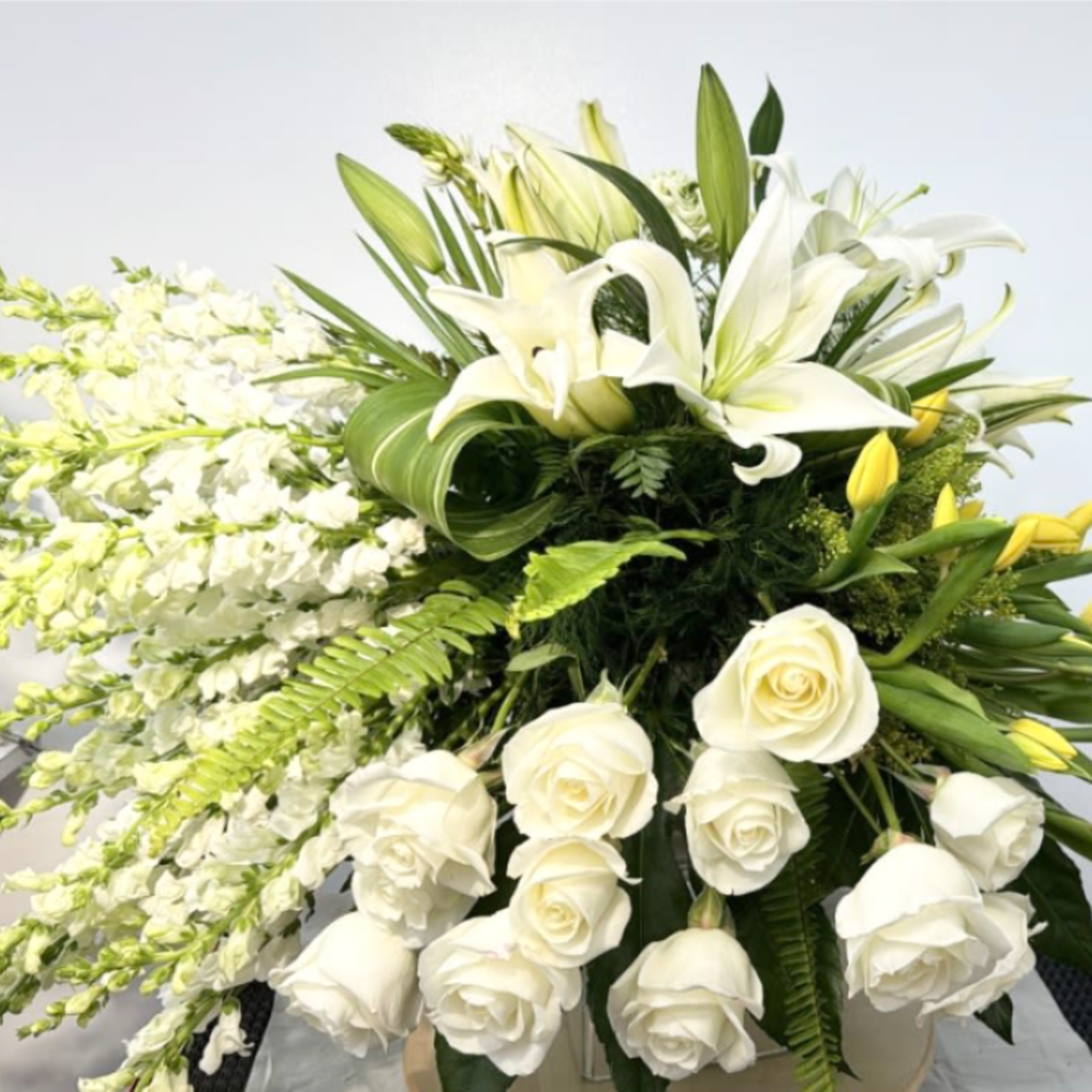 Large white floral arrangement with lilies, roses, and cascading blooms