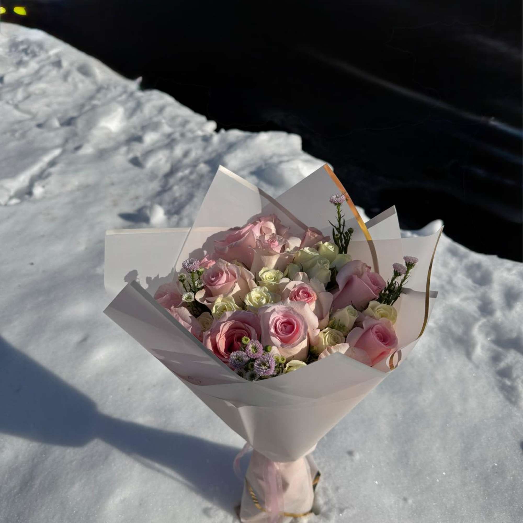Bouquet of pink and white roses wrapped in white paper