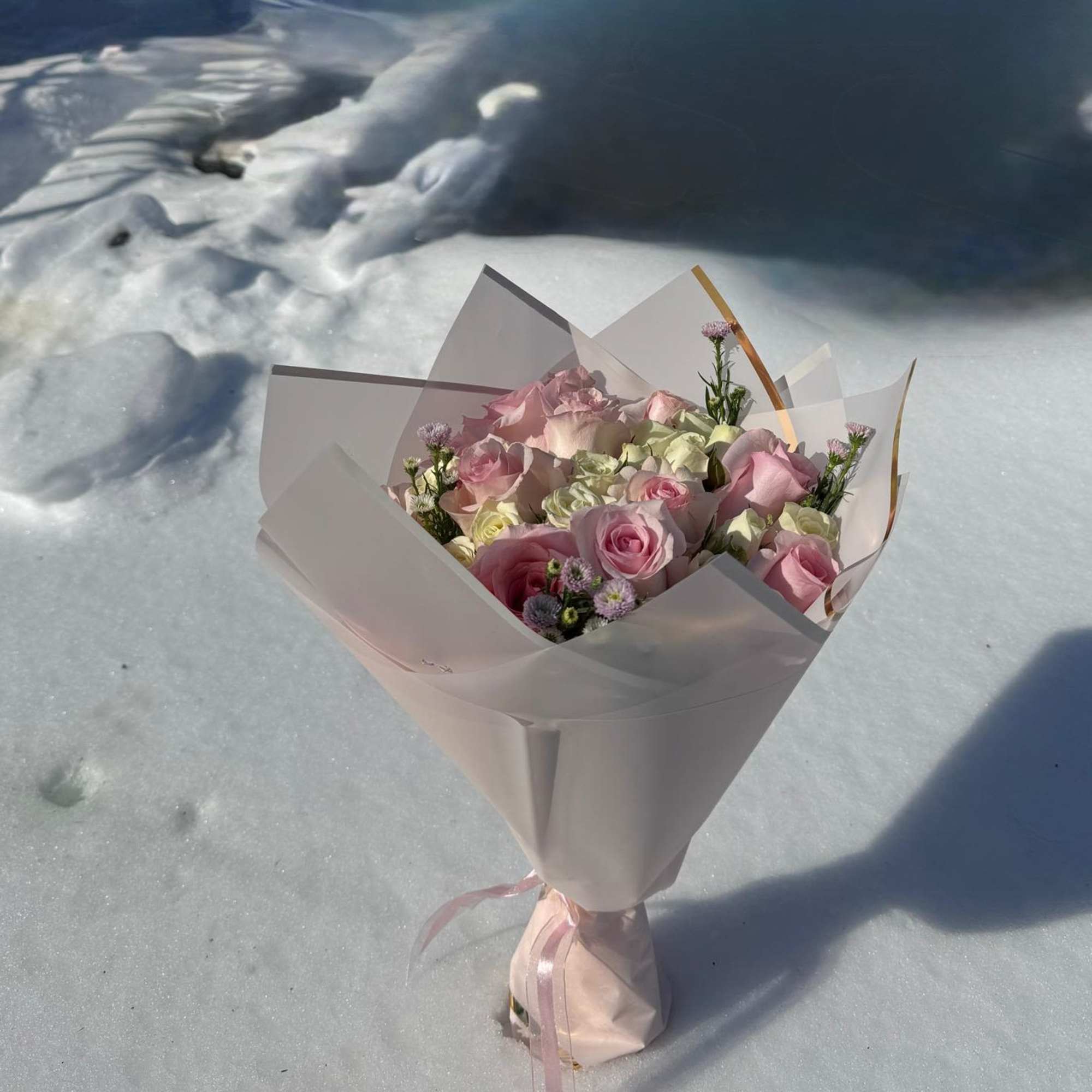 Pink rose bouquet wrapped in pale paper and ribbon