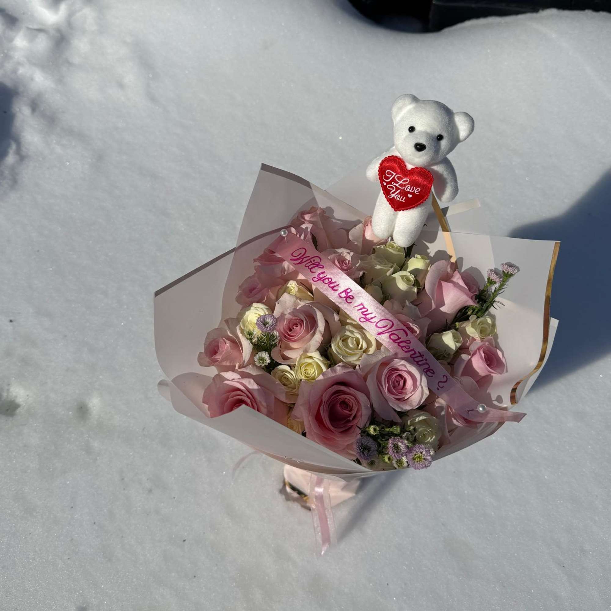 Pink and white rose bouquet with a teddy bear topper in snow