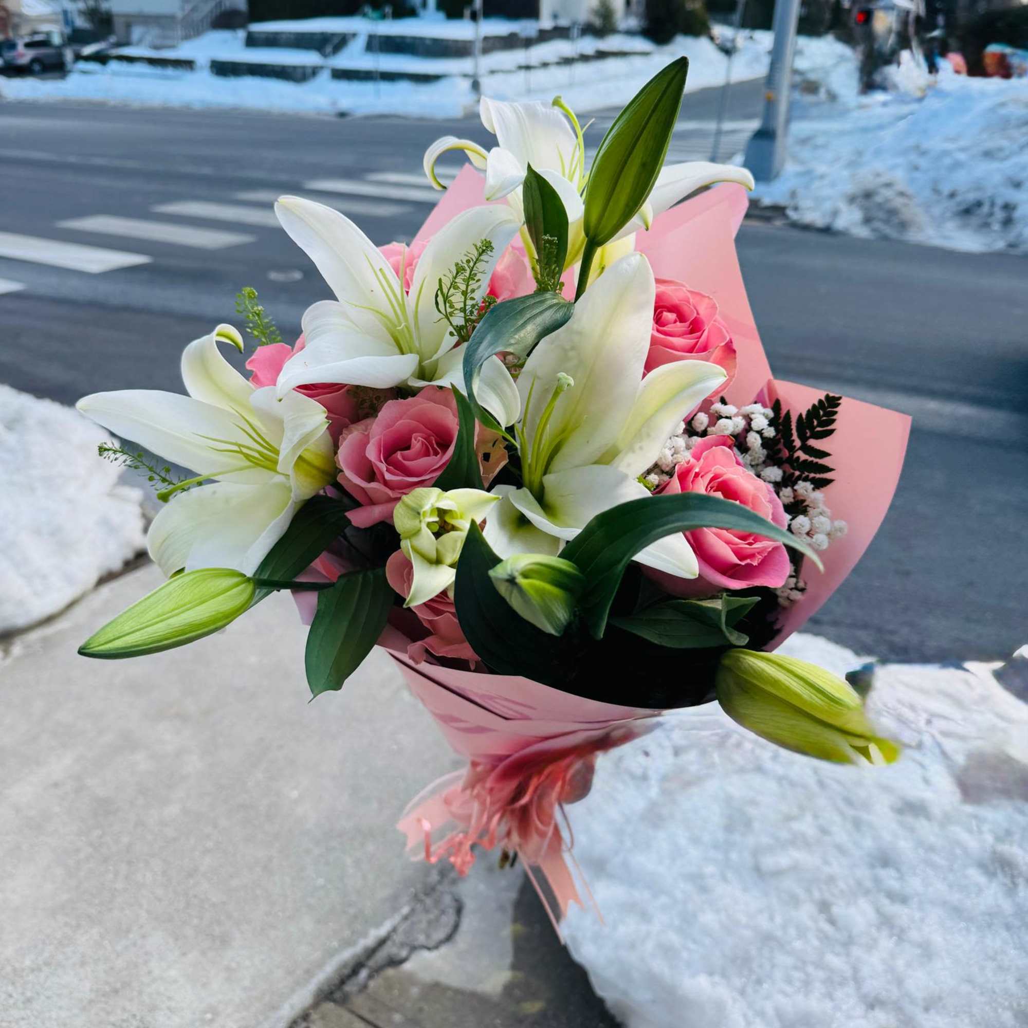 Pink roses and white lilies in pink wrapping outdoors
