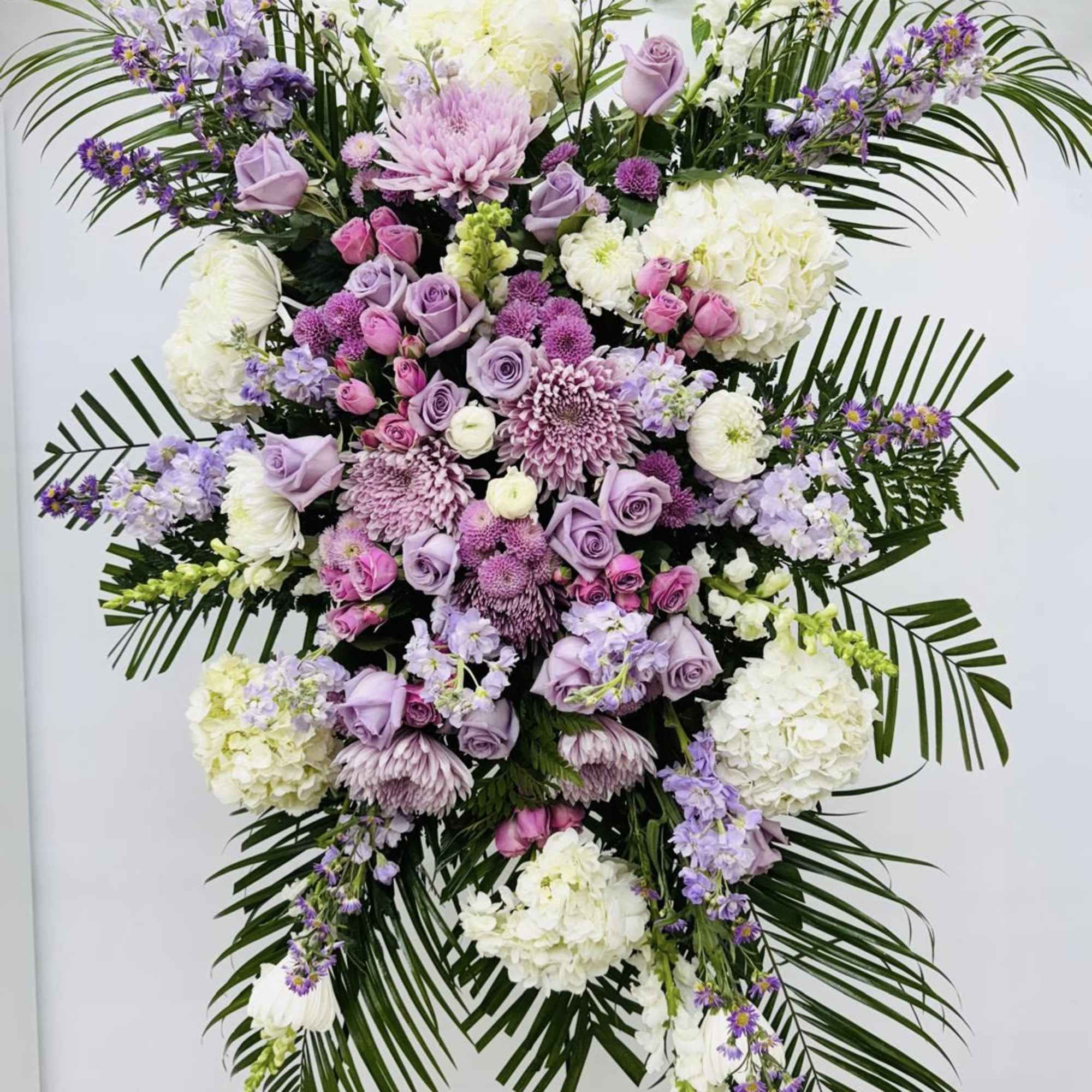 Large standing floral spray in lavender, pink, and white on a stand