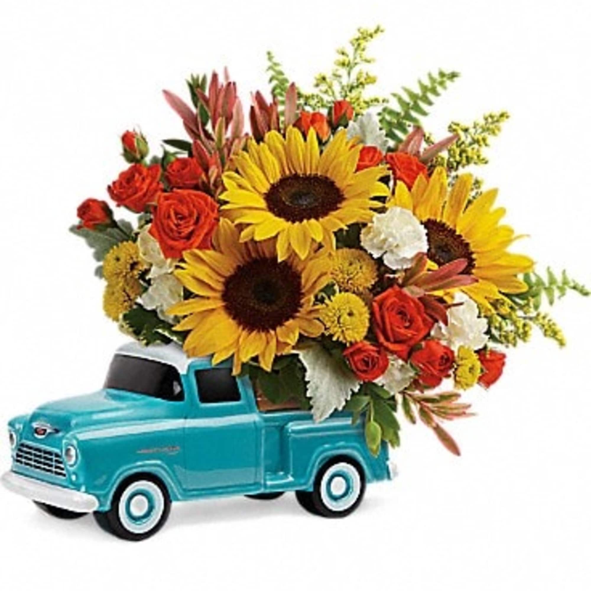 Bouquet of sunflowers and red roses in a turquoise toy truck