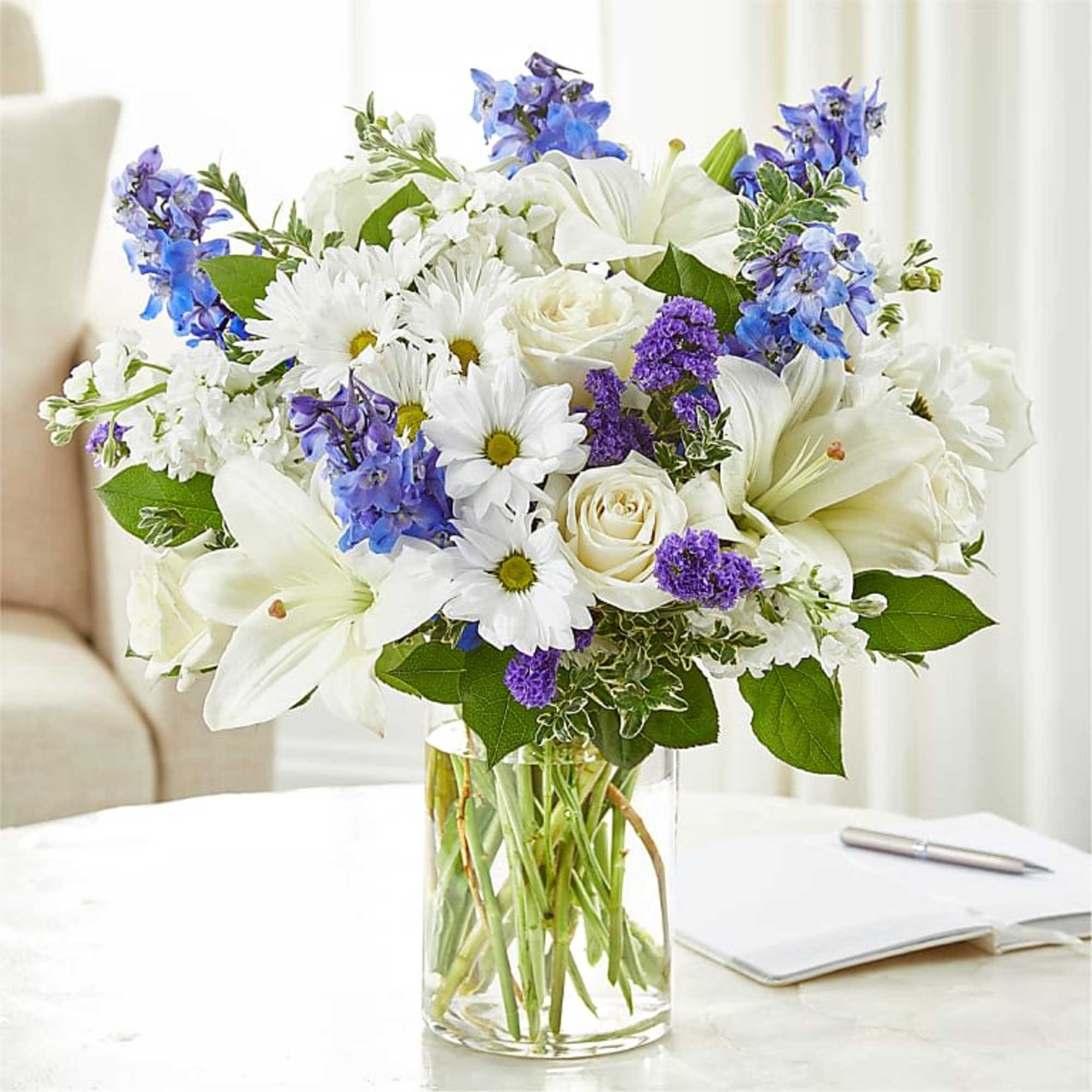 White and blue mixed bouquet in a clear glass vase