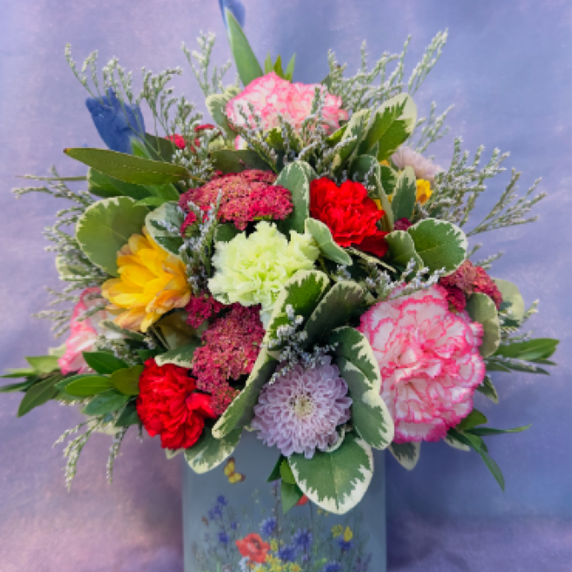 A cheerful garden-style arrangement featuring pink and red carnations, pale lavender accents, photo 2 of 2