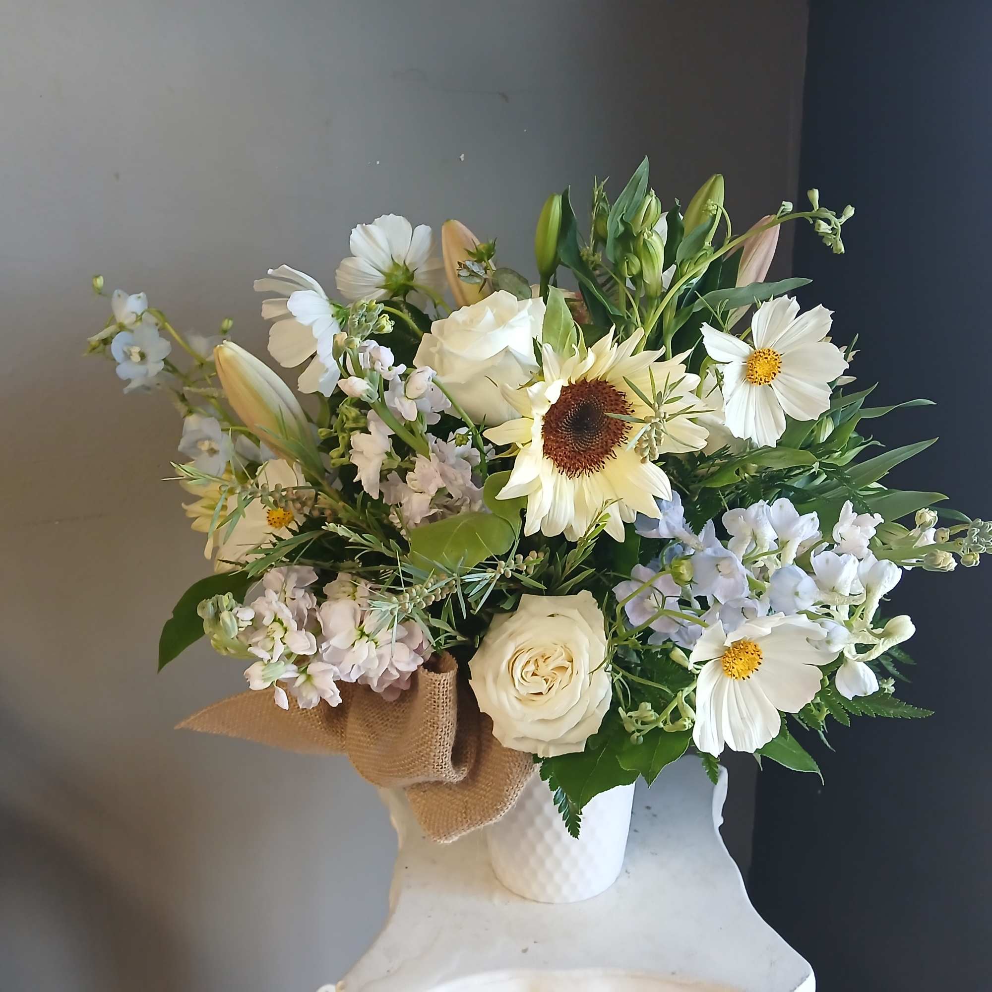 White and pale yellow mixed bouquet in a white vase with burlap wrap