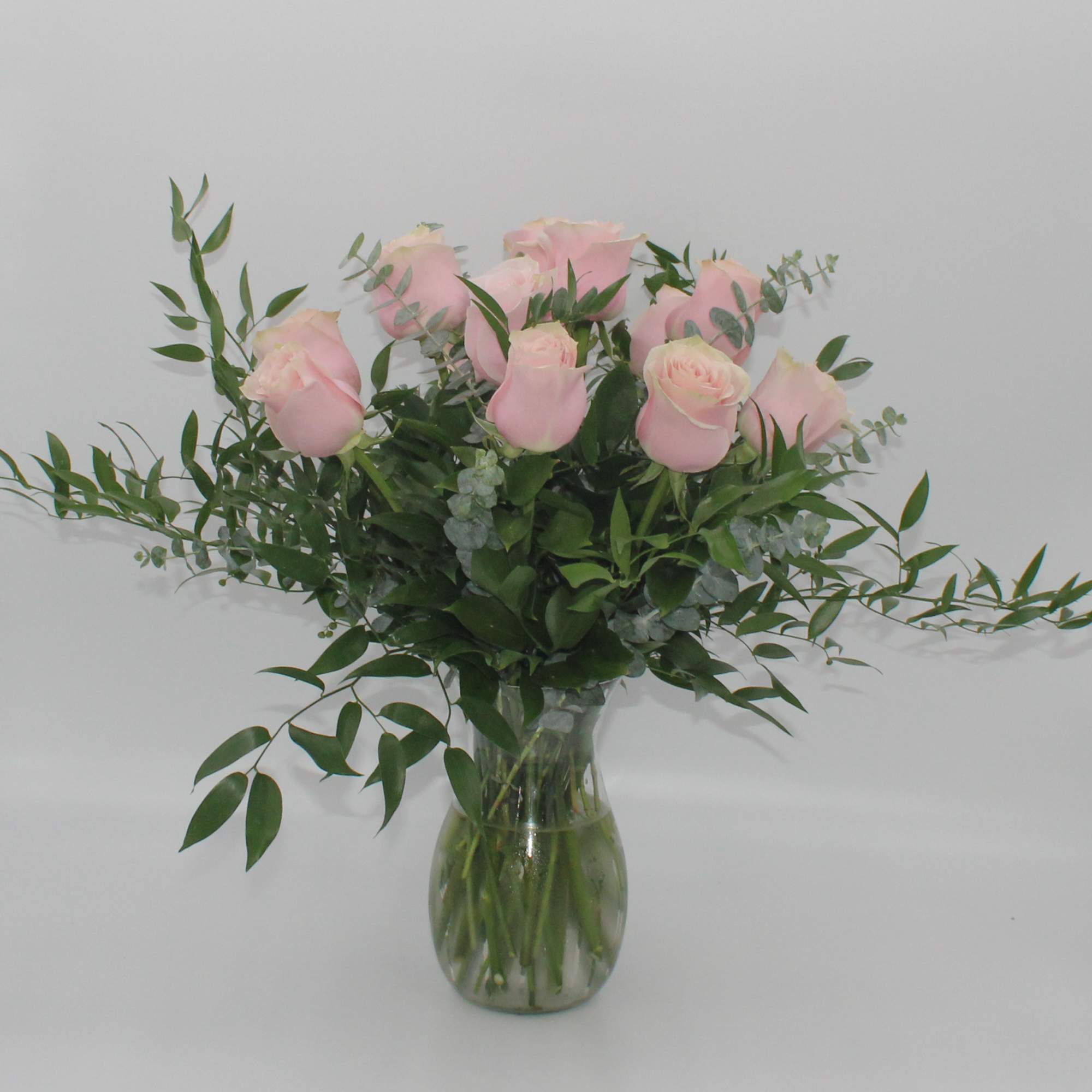 Pink roses in a clear glass vase with airy greenery