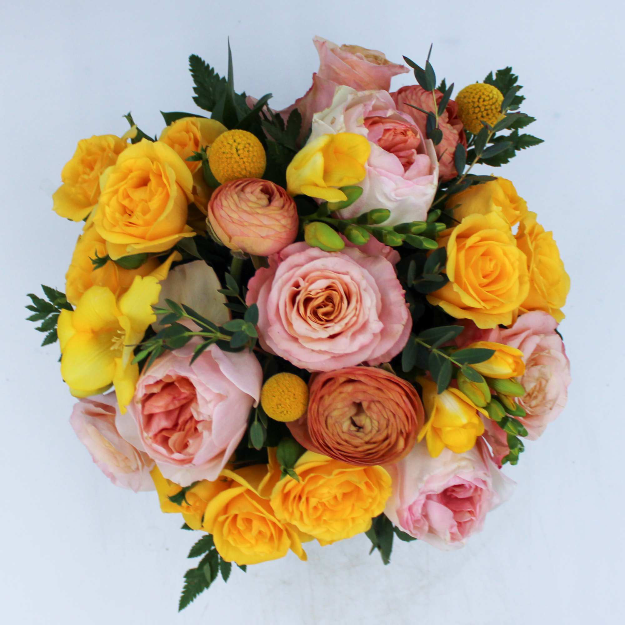 Round bouquet of pink and yellow roses with small yellow accent blooms