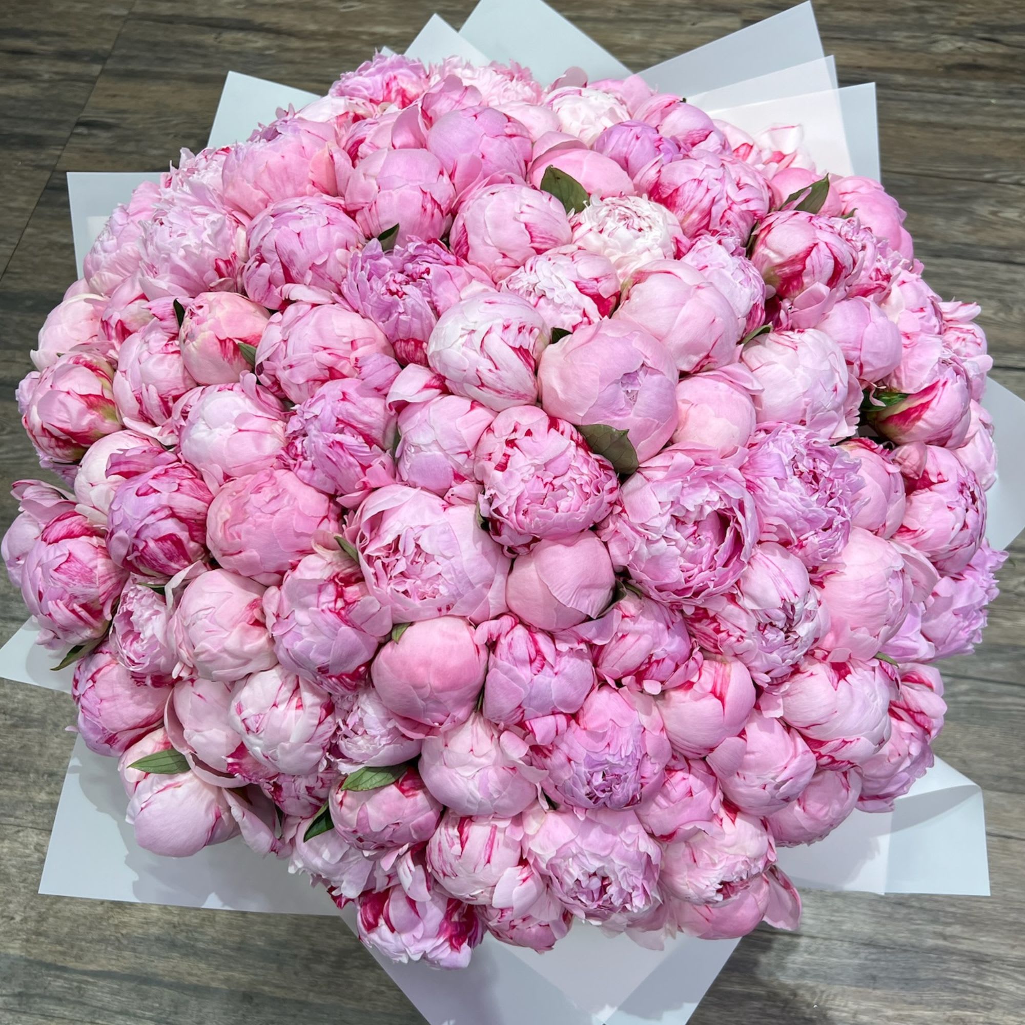 Large bouquet of pink peonies wrapped in white paper