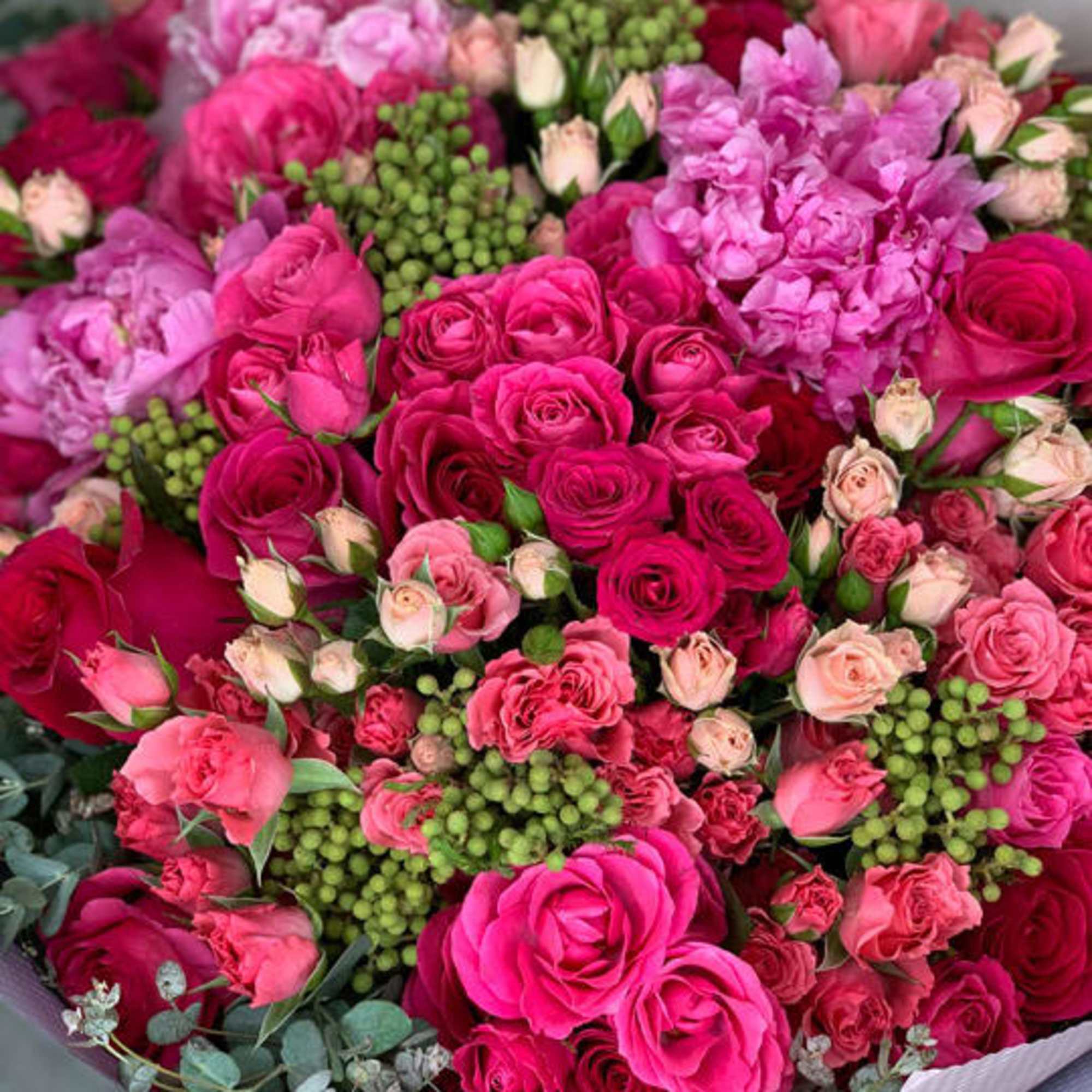 Bouquet of pink and magenta roses with green berries and eucalyptus
