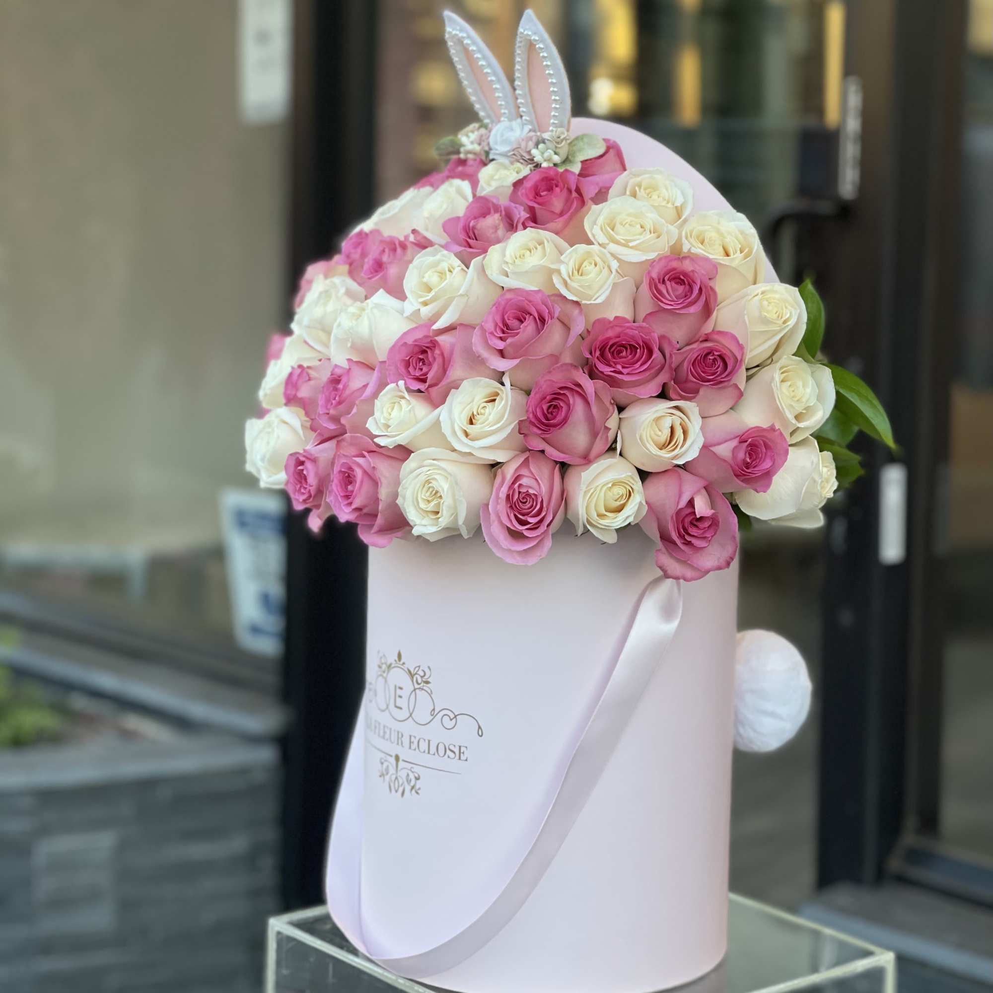 Pink and white roses in a pale pink hatbox with bunny ears