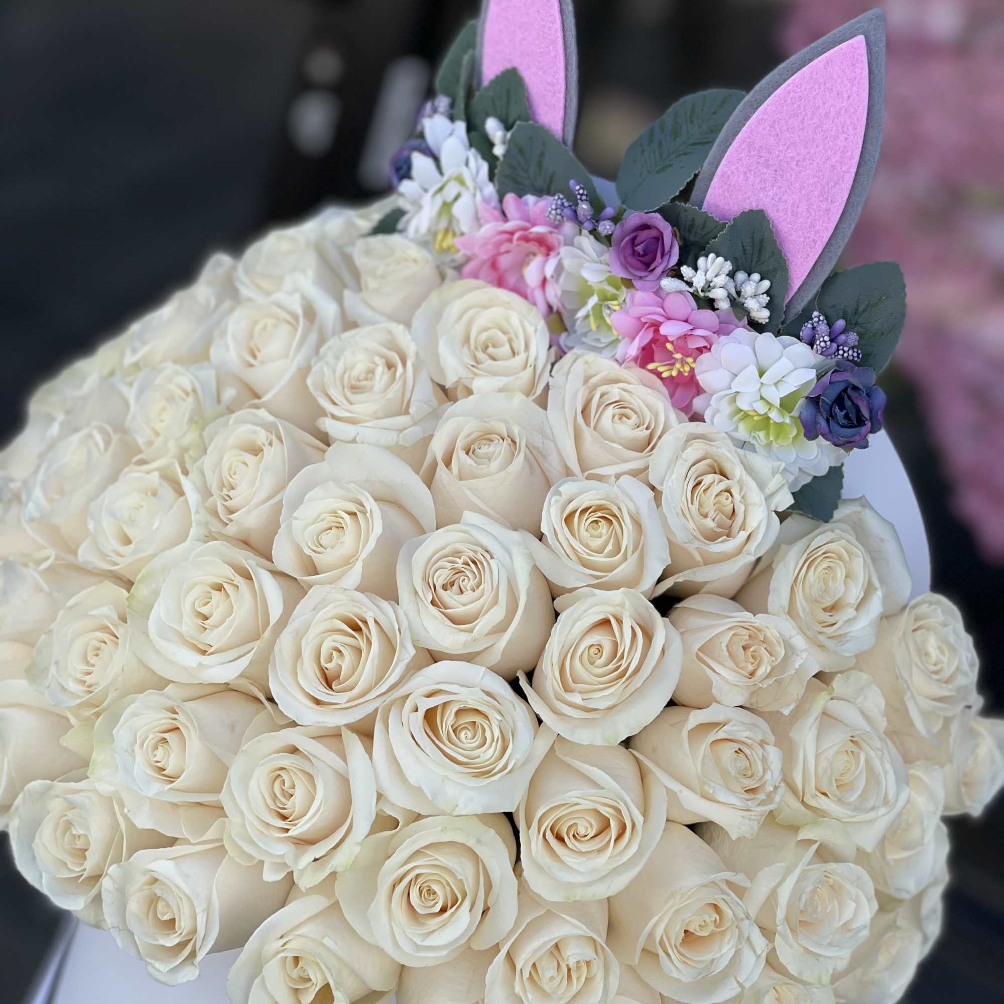 Bouquet of cream roses with pink and purple floral accents and bunny ears
