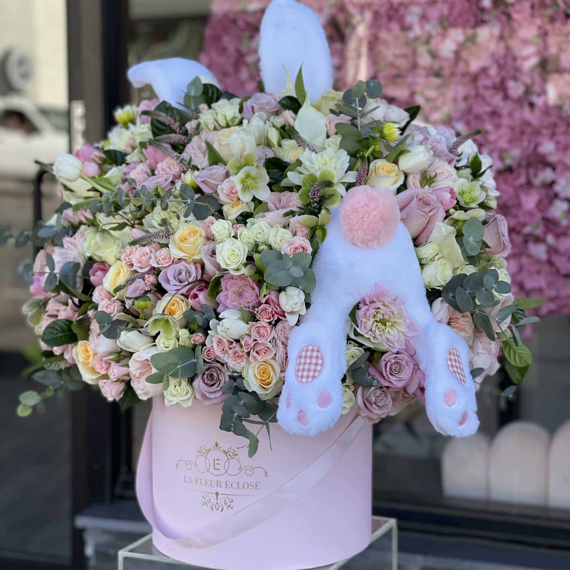 Pastel flower arrangement in a pink box with a plush bunny