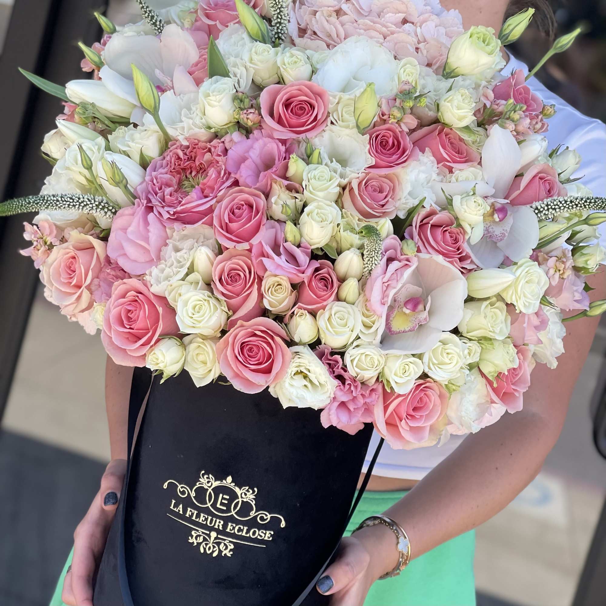 Large bouquet of pink and white roses with orchids in a black box