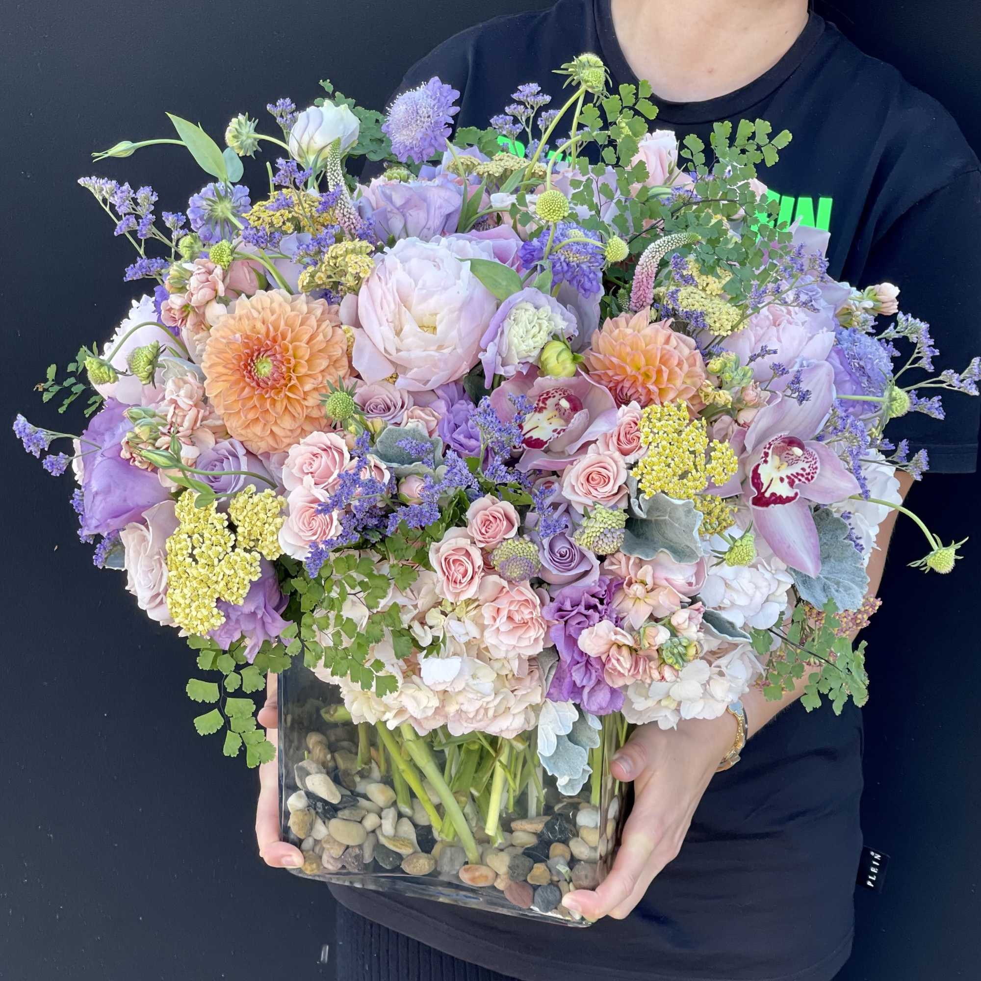 Large pastel bouquet in a glass vase with pink, lavender, and peach flowers