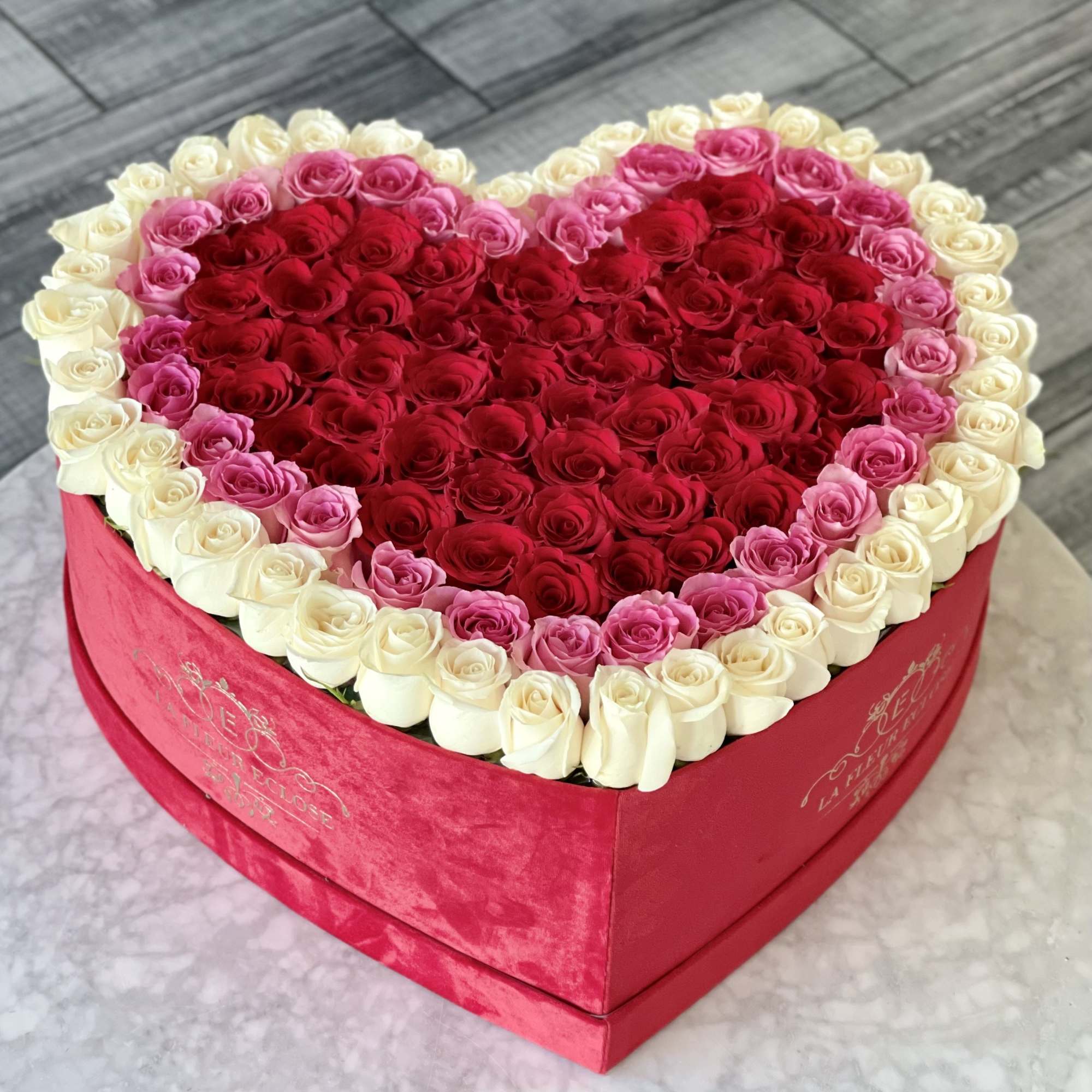 Heart-shaped box filled with red, pink, and white roses