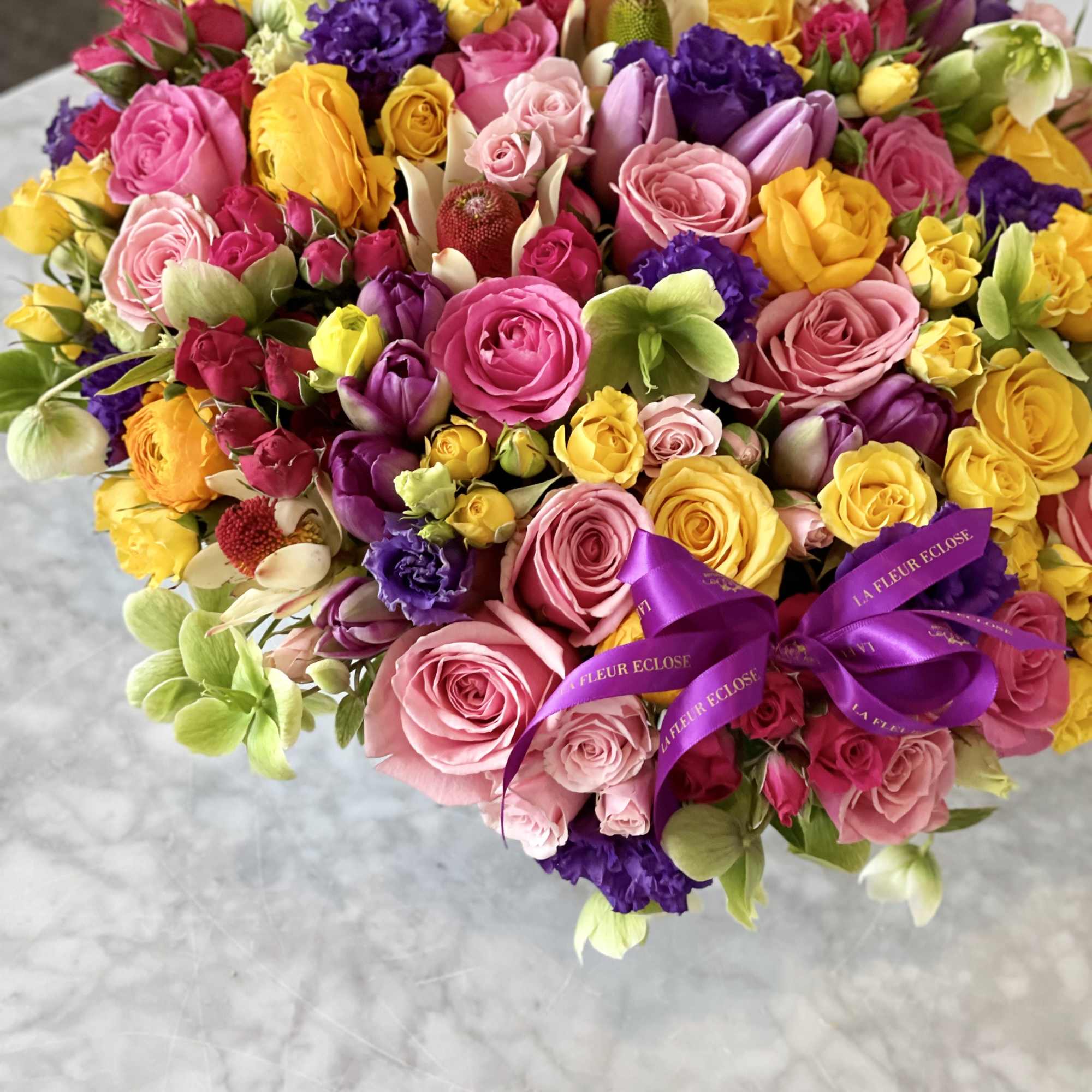 Large bouquet of pink, yellow, and purple roses with ribbon