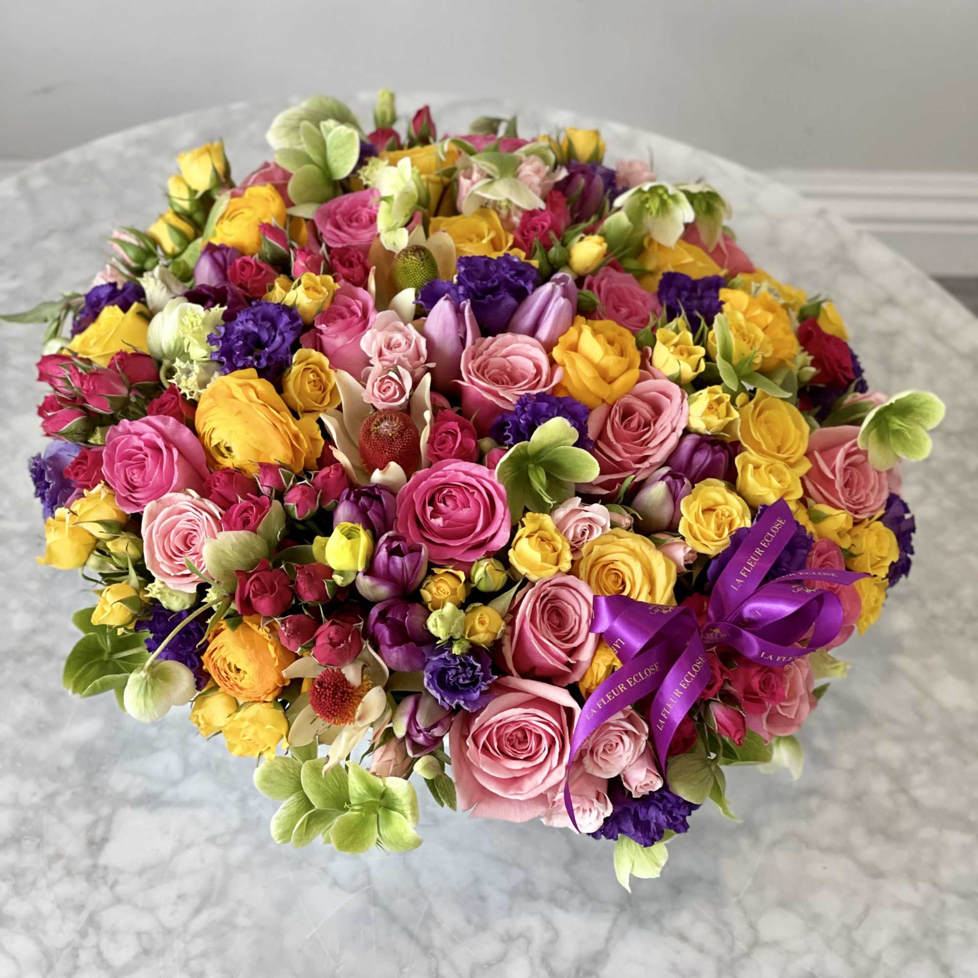 Large round bouquet of pink, yellow, purple, and white flowers