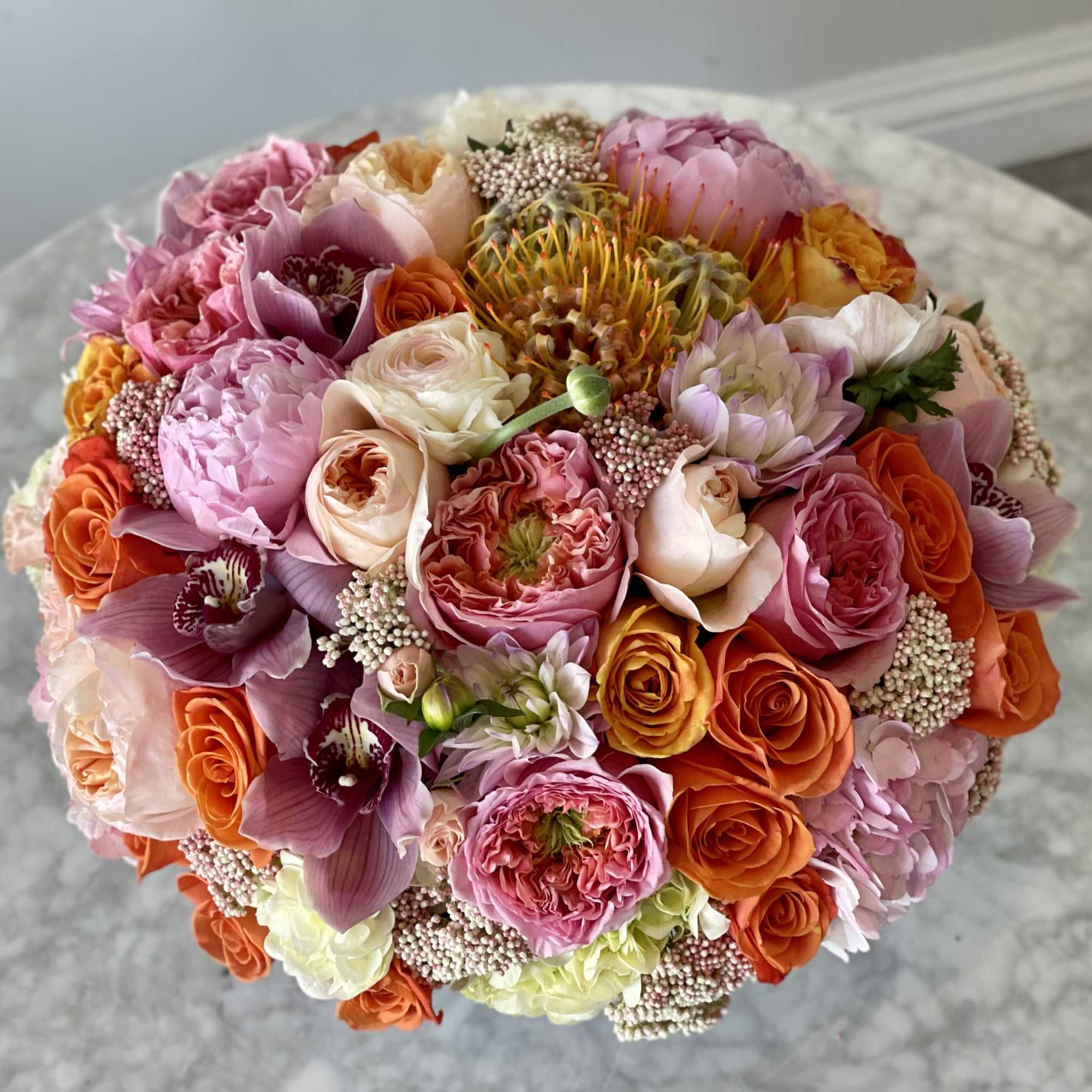 Round bouquet of pink, orange, and cream flowers