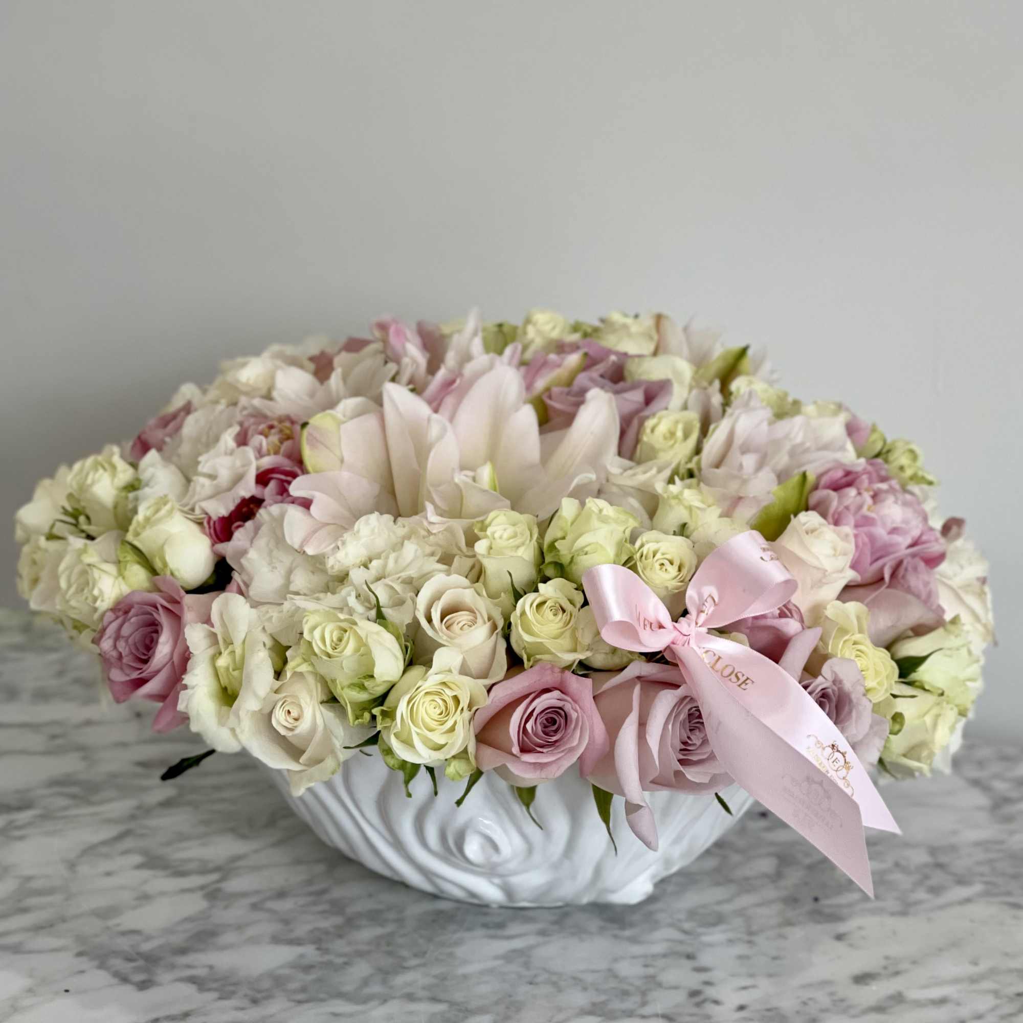 Low floral arrangement of pink and white roses in a white bowl vase