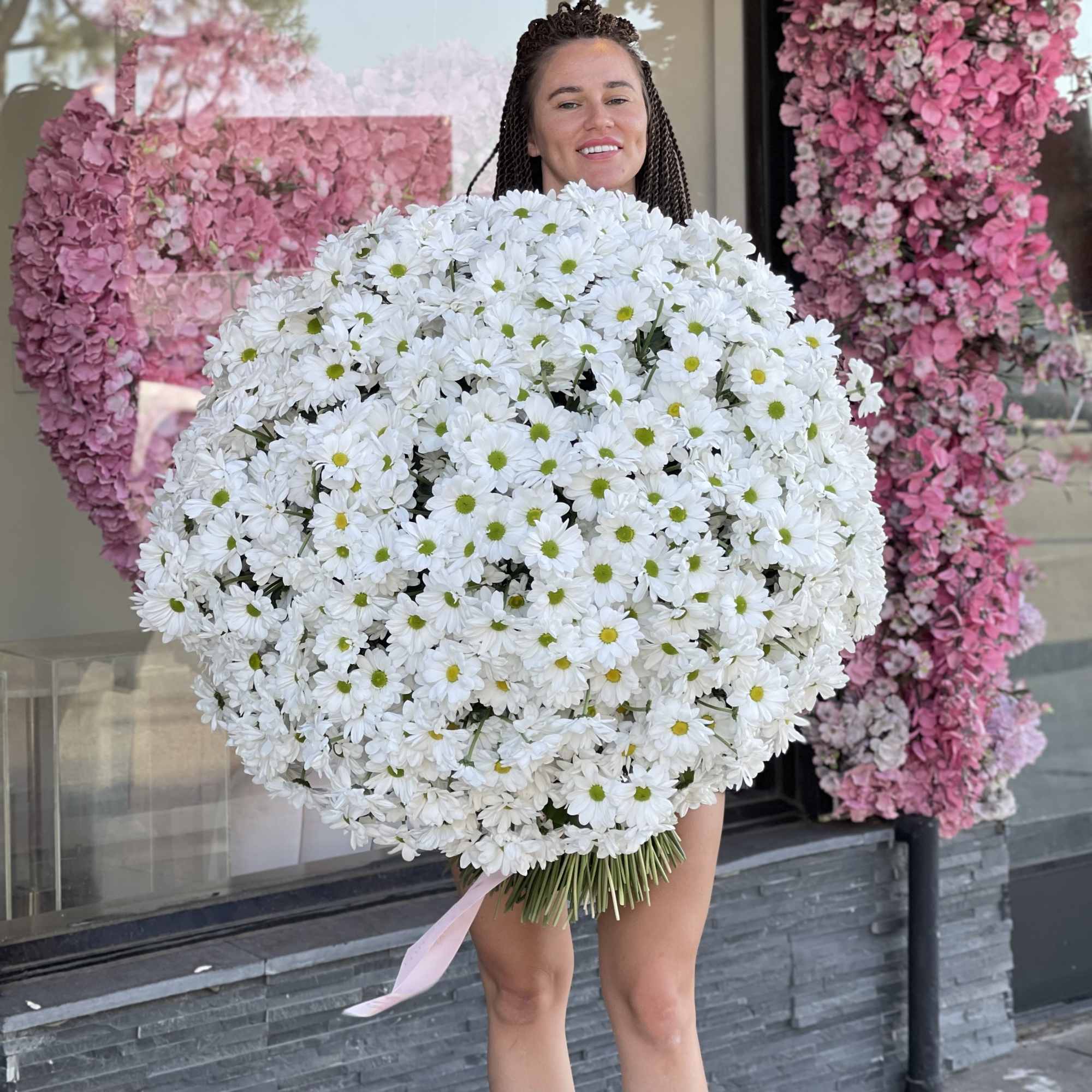 Woman holding an oversized bouquet of white daisies