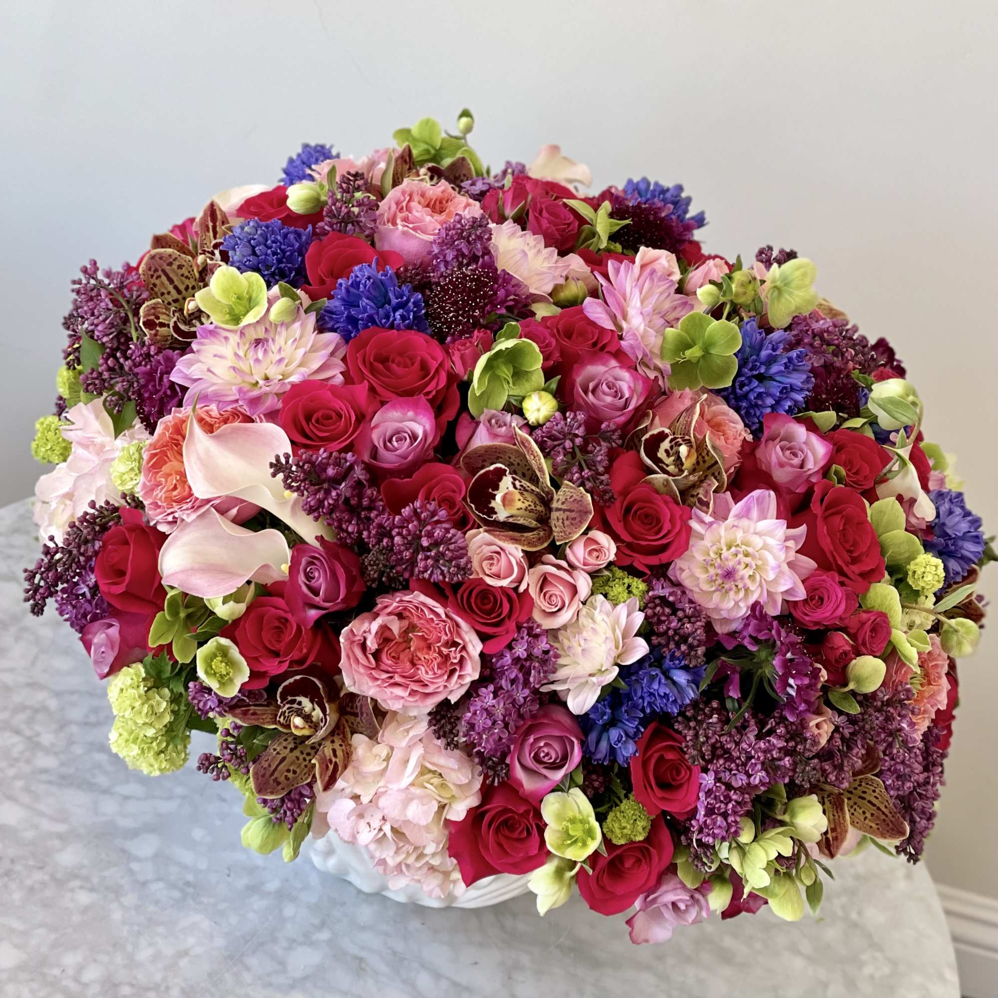 Large bouquet of pink, purple, and red flowers in a white vase