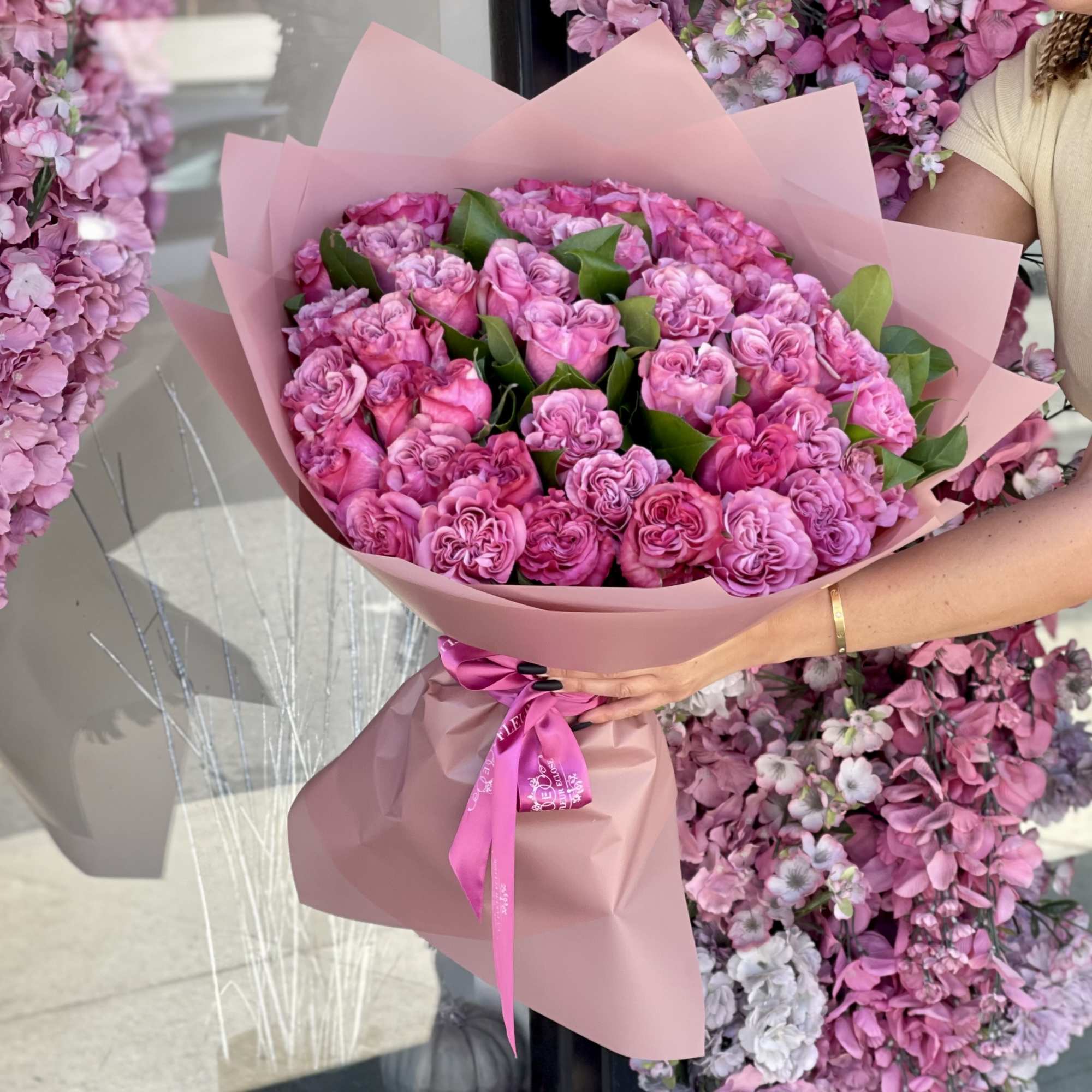 Large bouquet of pink roses wrapped in blush paper with a ribbon