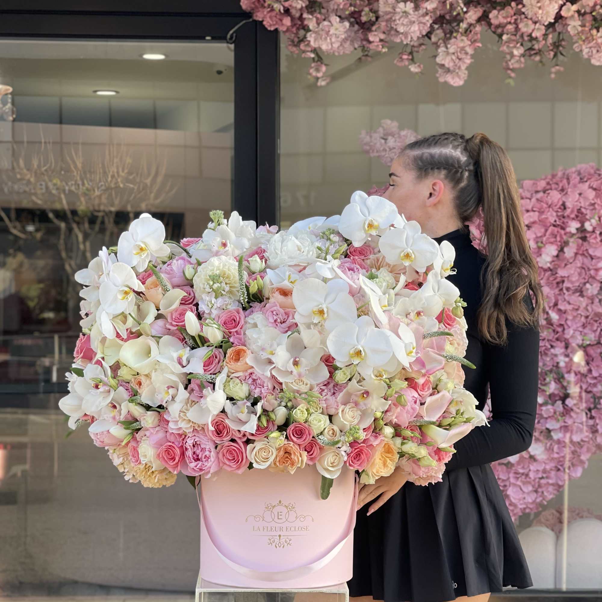 Large pink and white floral arrangement in a round pink box