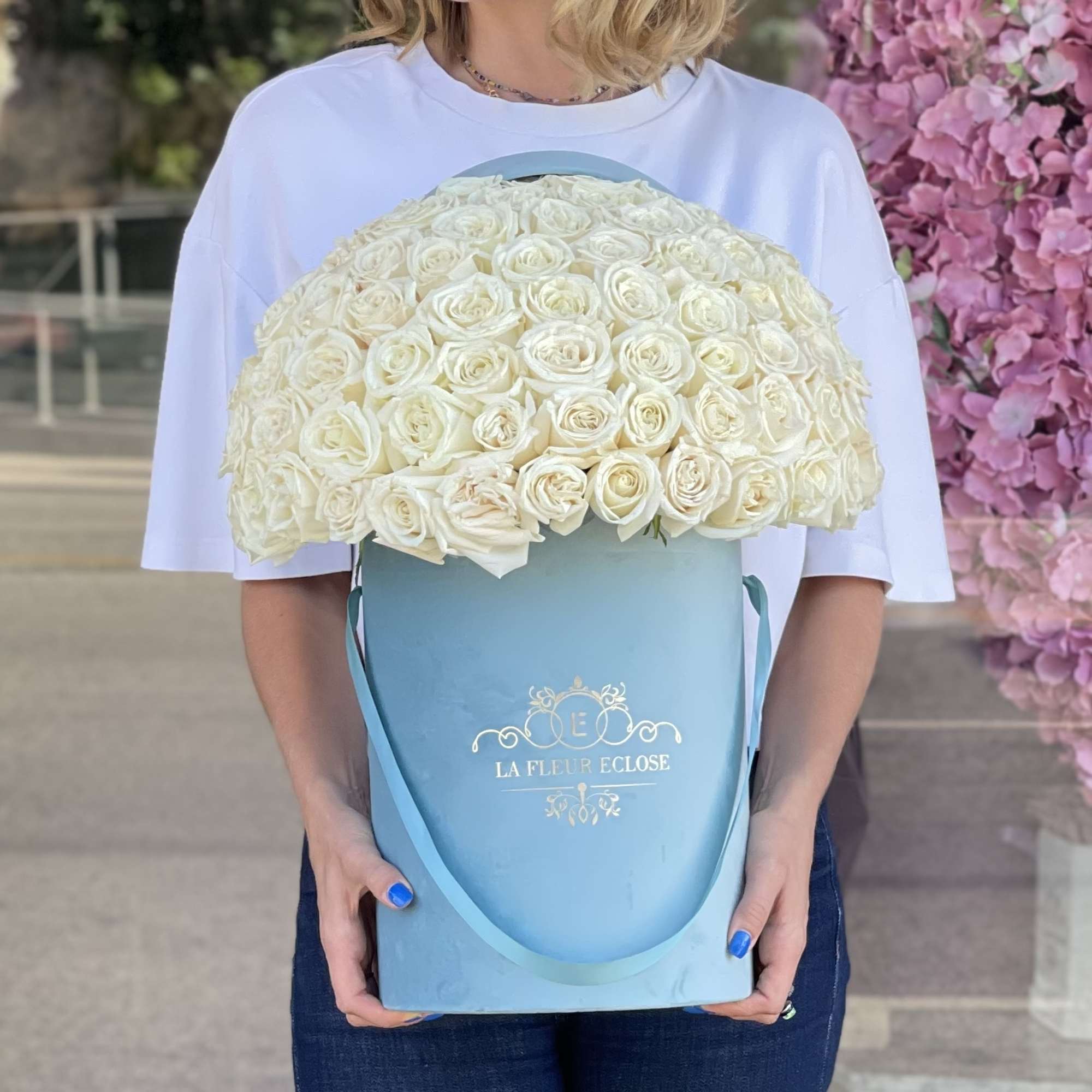 Woman holding a large blue box of white roses