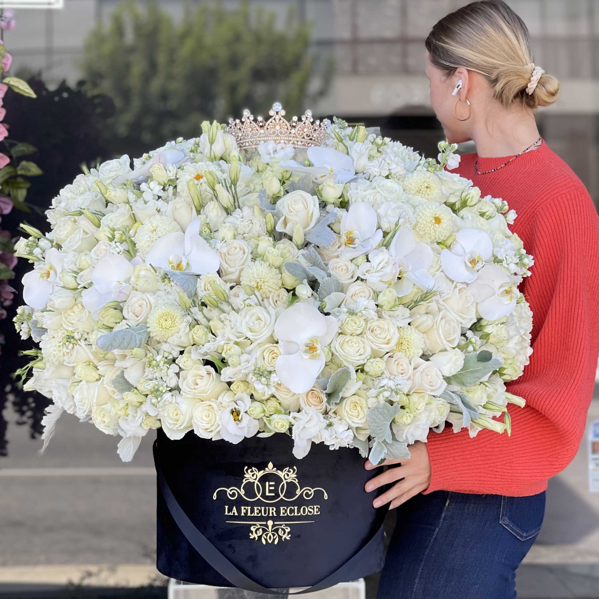 Large white floral arrangement in a black box with a crown on top