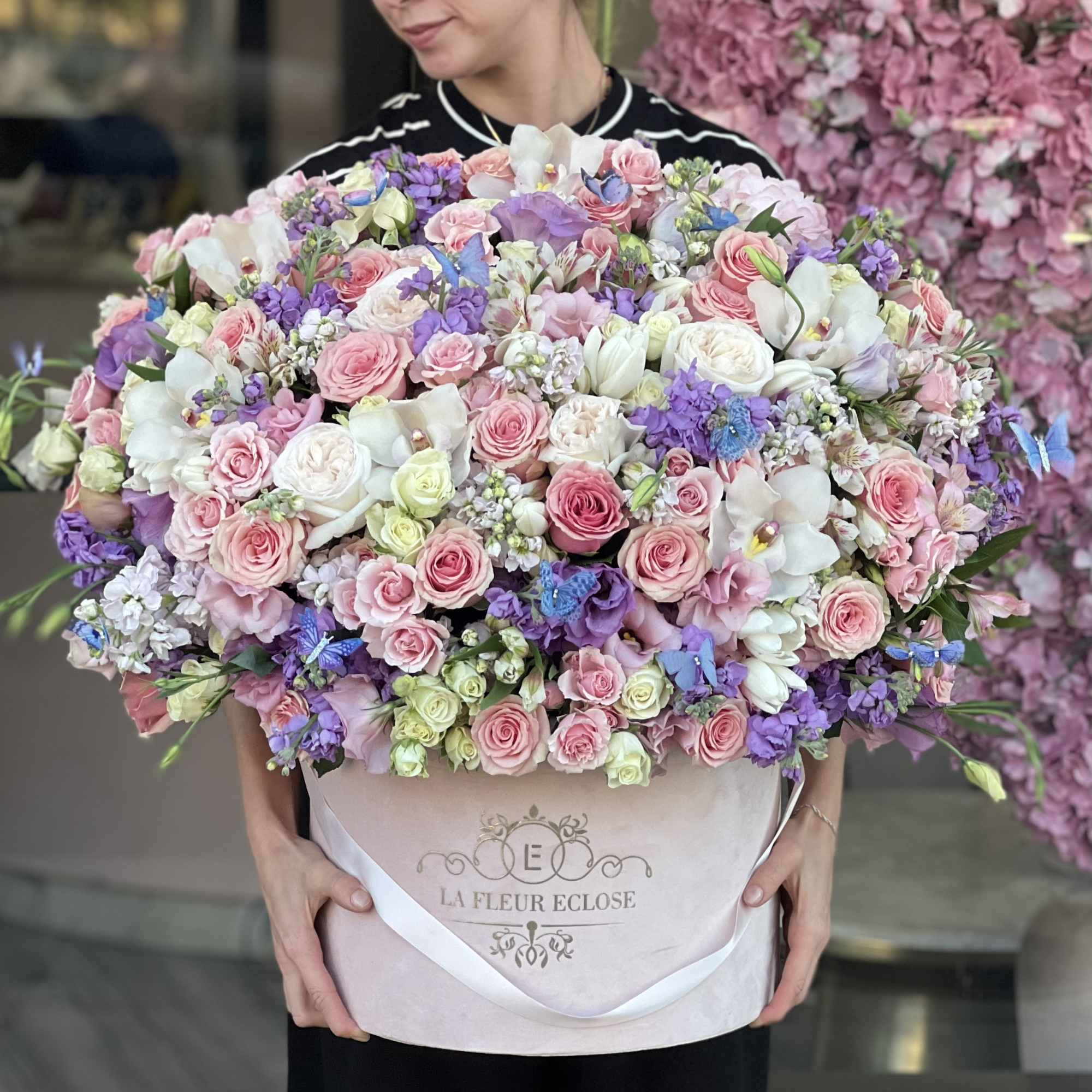 Large pastel bouquet of pink, white, and purple flowers in a round box
