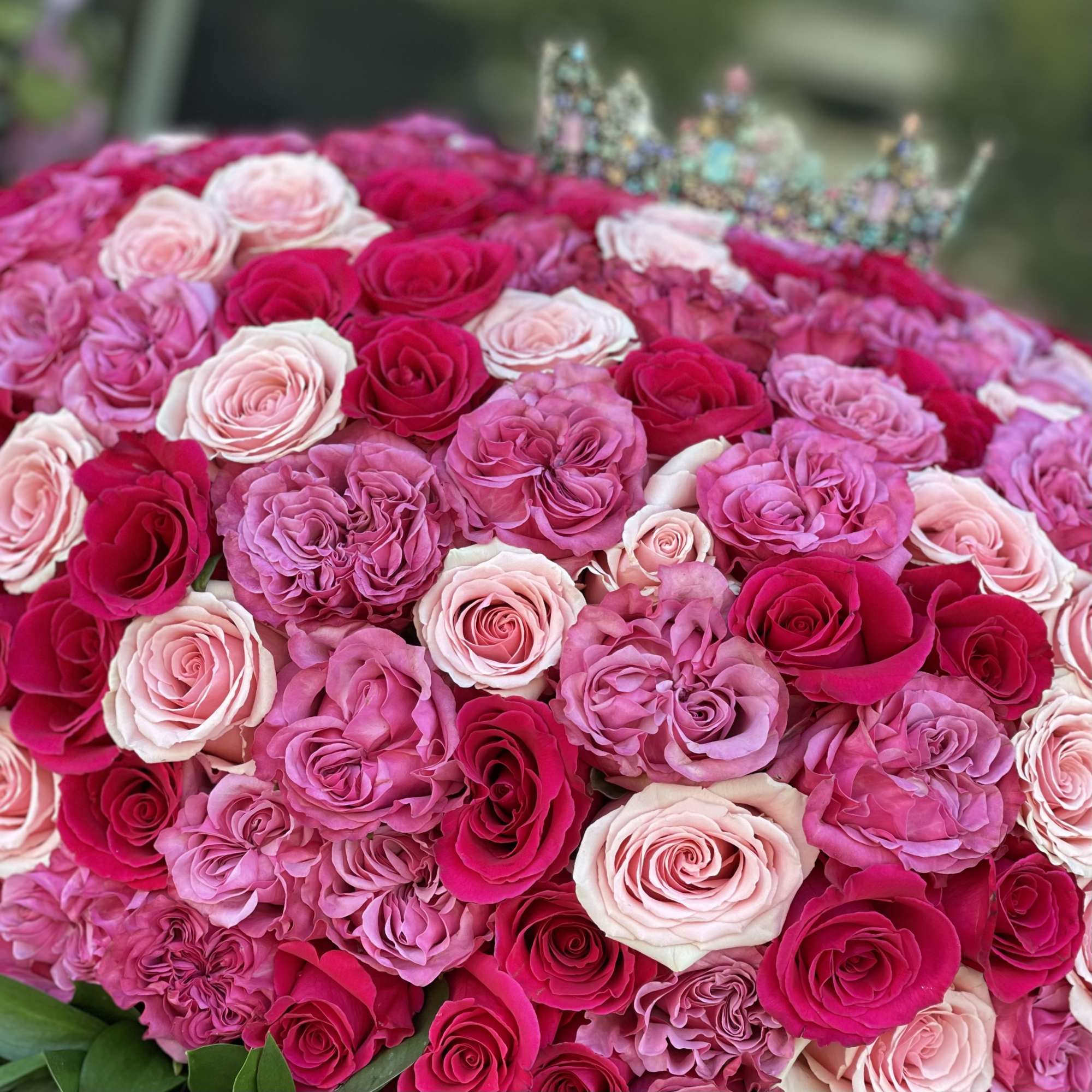 Heart-shaped arrangement of pink and red roses with a jeweled crown on top