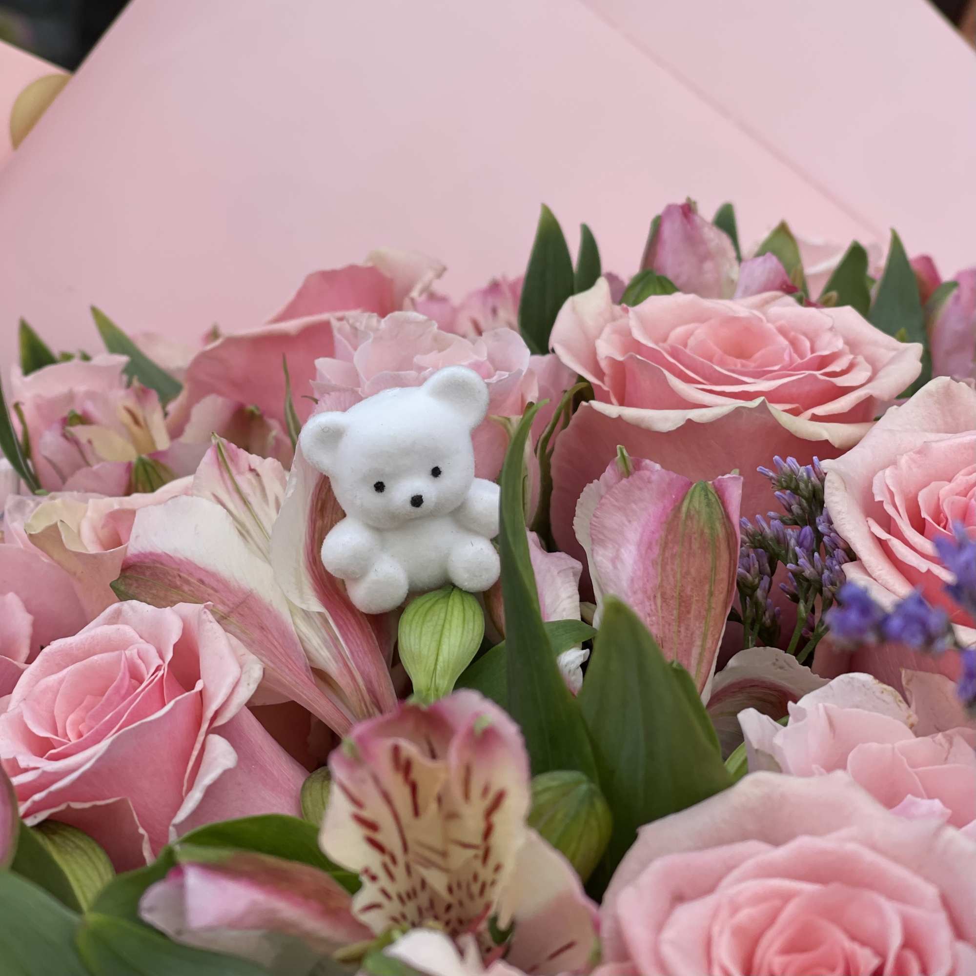 Pink roses and alstroemeria with a small white teddy bear