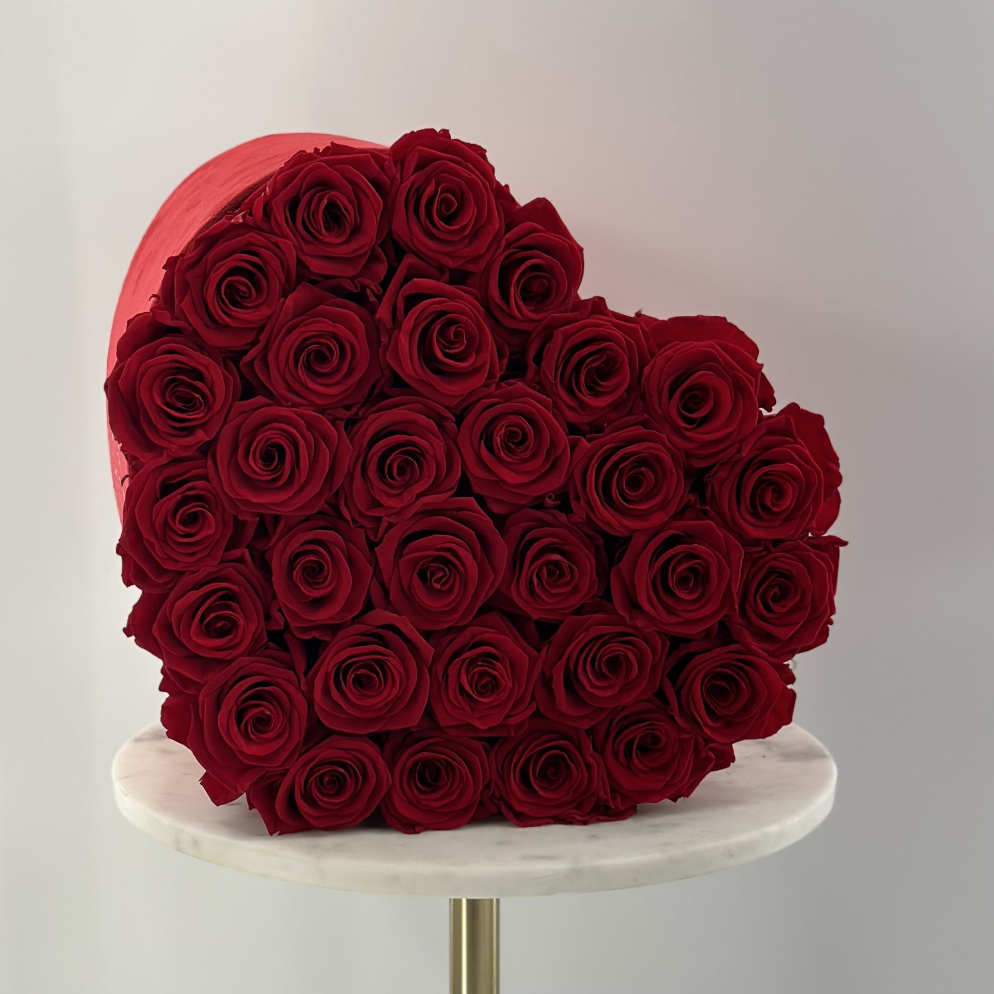 Heart-shaped bouquet of red roses on a round pedestal