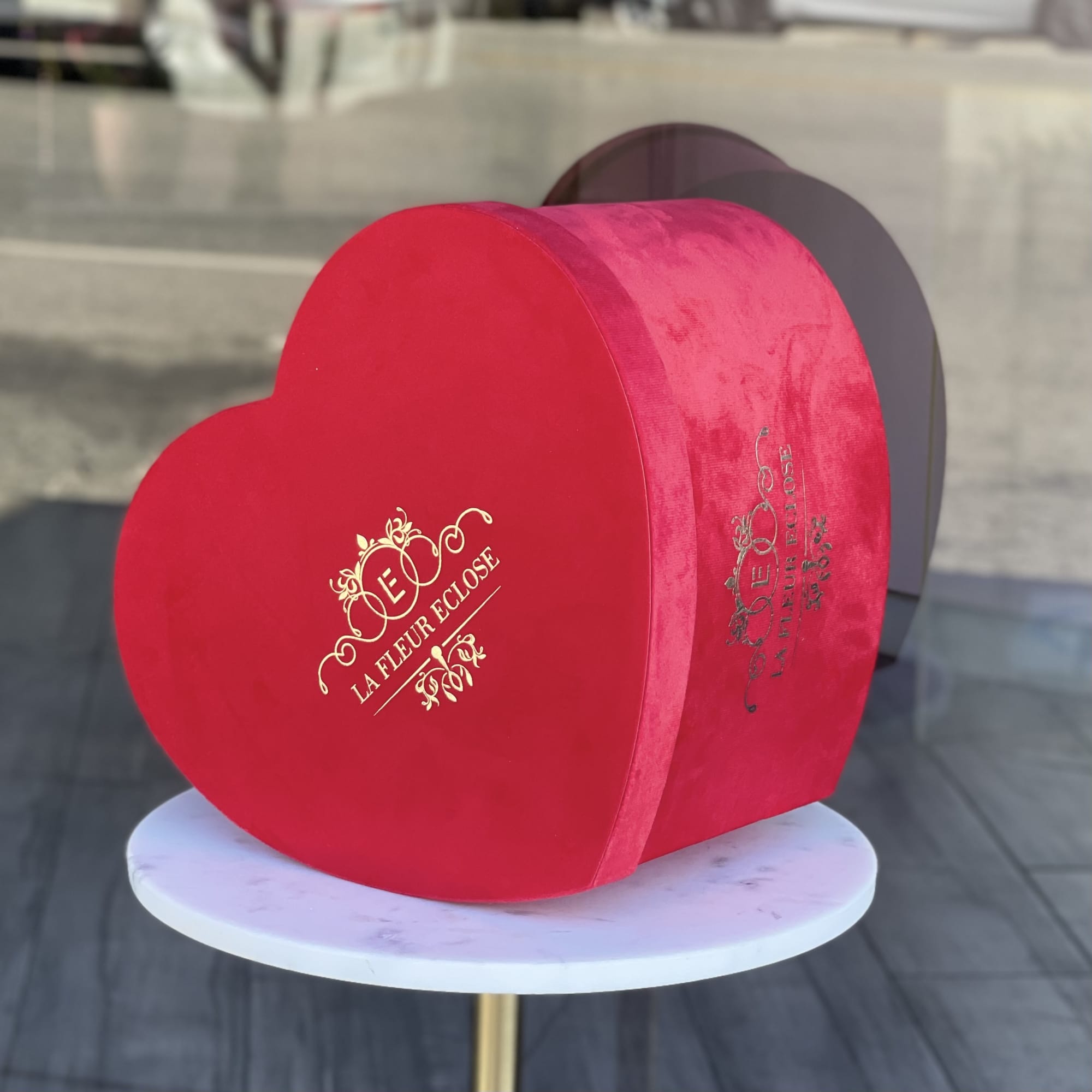 Red heart-shaped gift box on a round white table