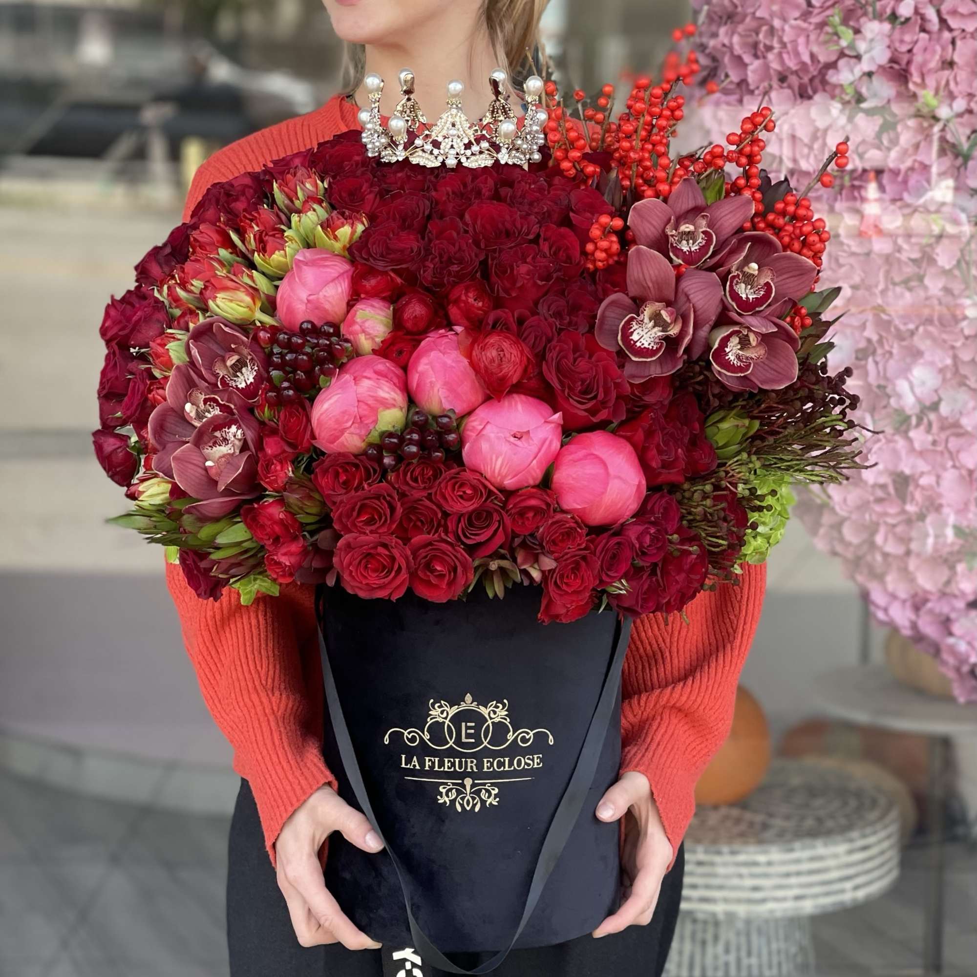 Large red and pink bouquet in a black hatbox with orchids and roses