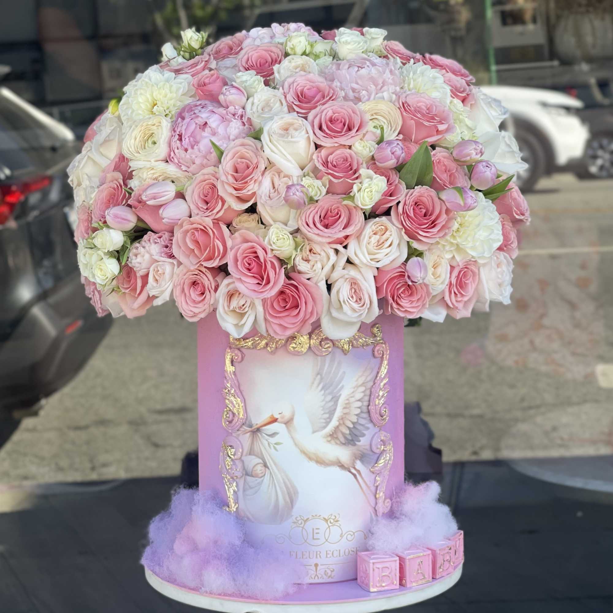 Large pink and white rose arrangement in a decorated round box