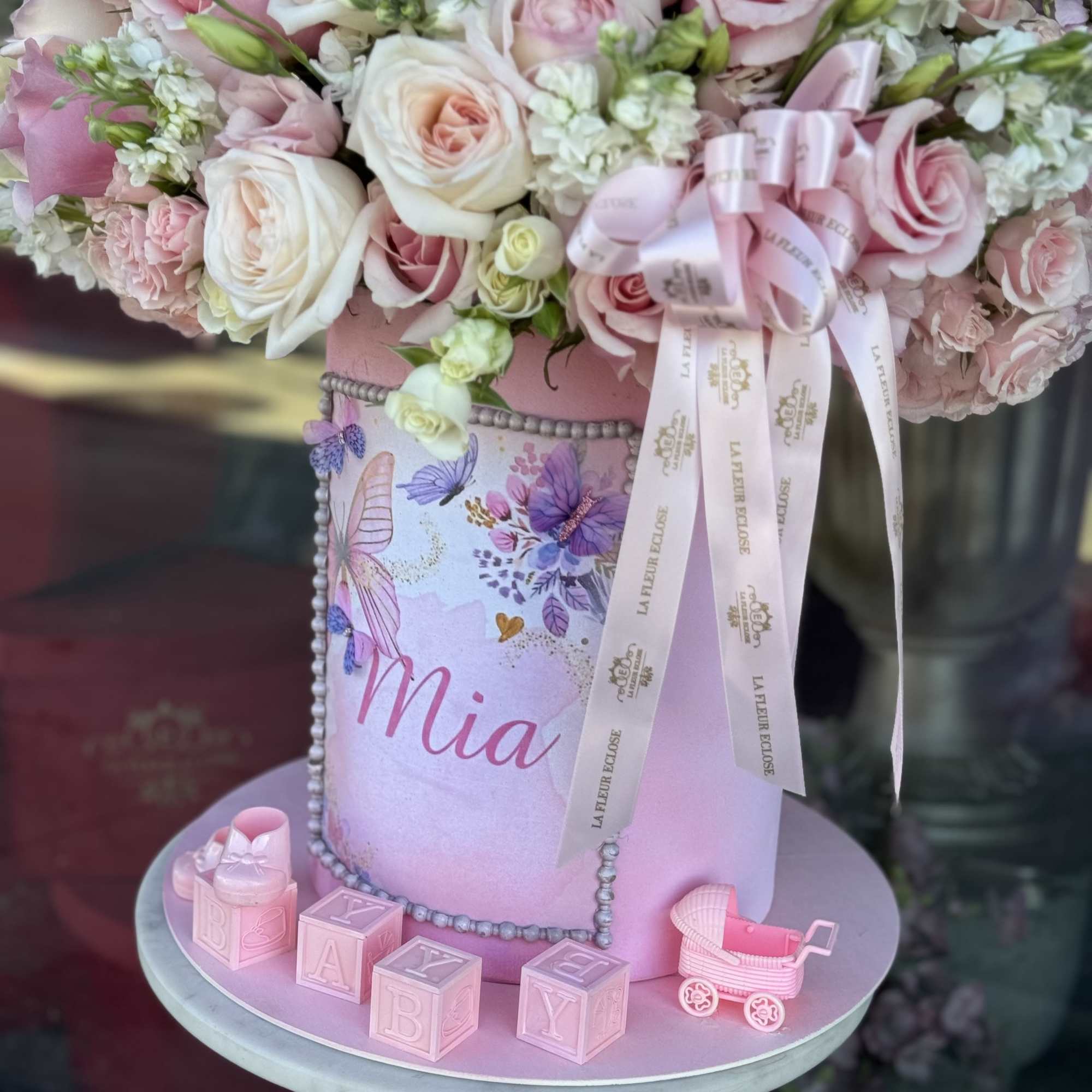 Pink and white rose arrangement in a decorated pastel box with baby blocks and a toy stroller