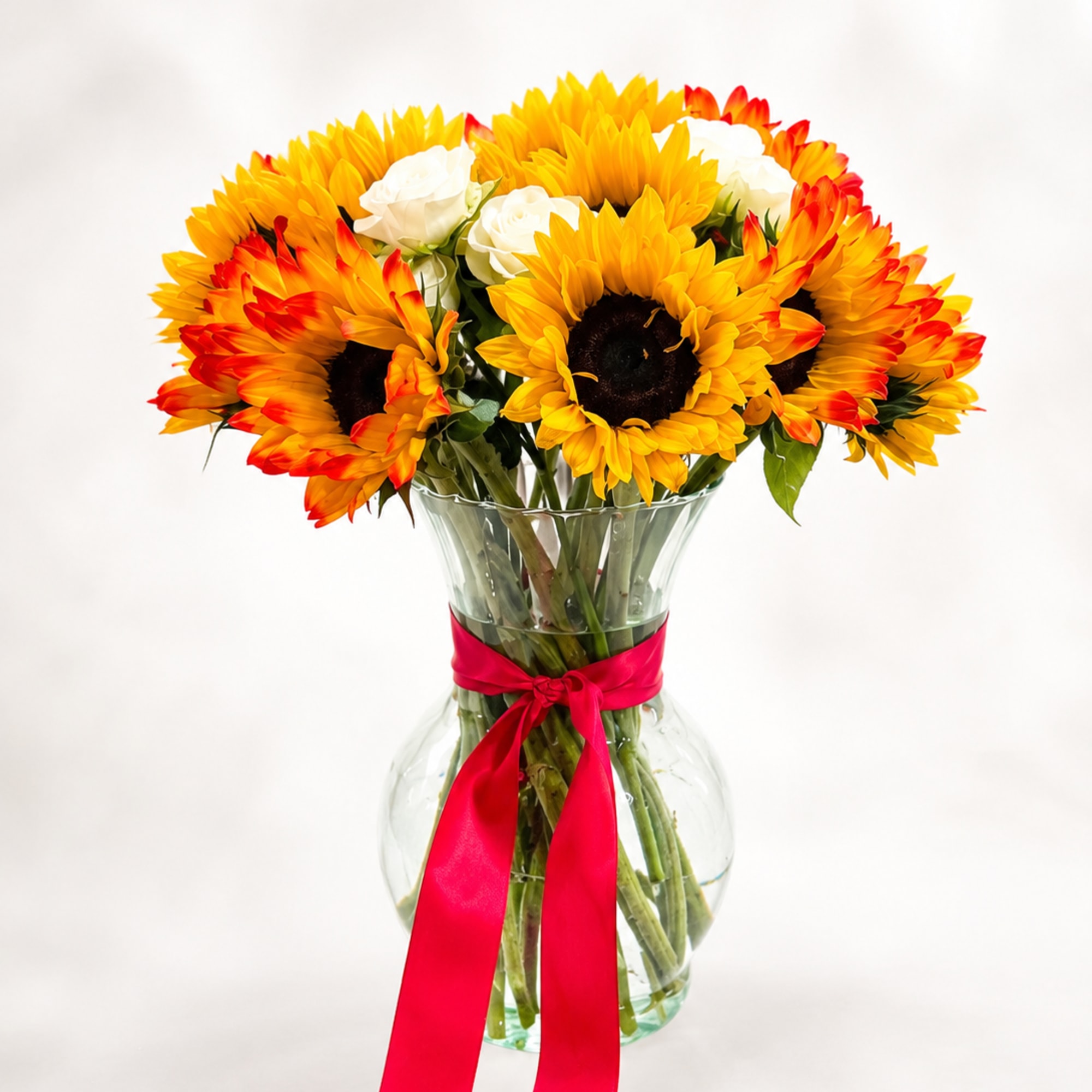 Sunflower bouquet in a clear glass vase with a red ribbon