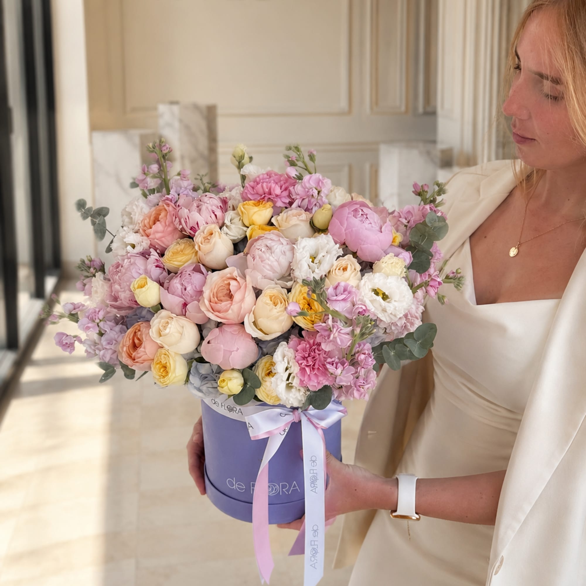 Woman holding a large pastel bouquet in a lavender hat box