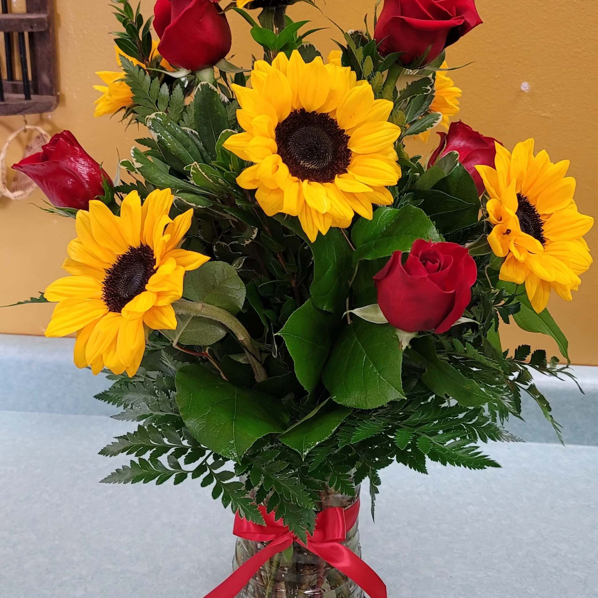 Sunflowers (two different sizes), red roses, greenery and clear vase. 