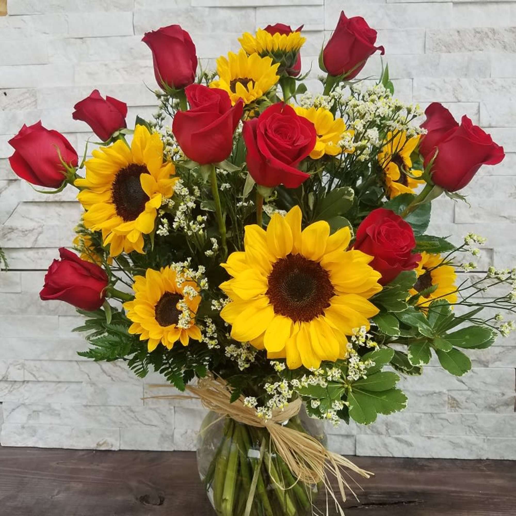 Sunflowers (two different sizes), red roses, greenery and clear vase. 