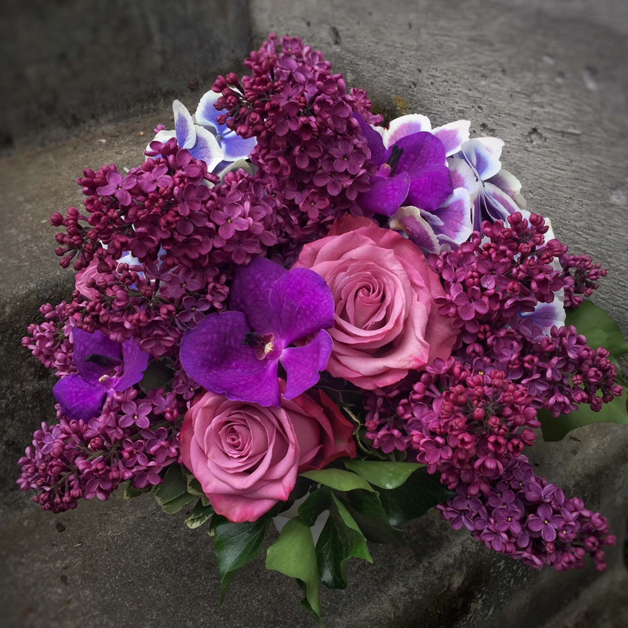 Pink roses and purple orchids with magenta lilacs in a bouquet