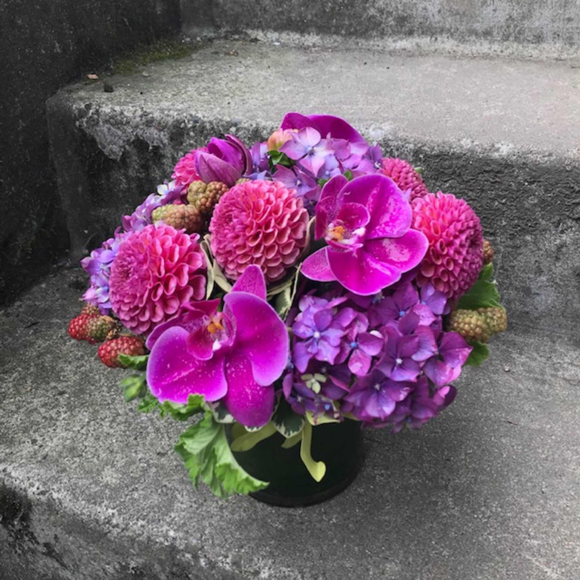 Purple and pink floral arrangement in a black vase