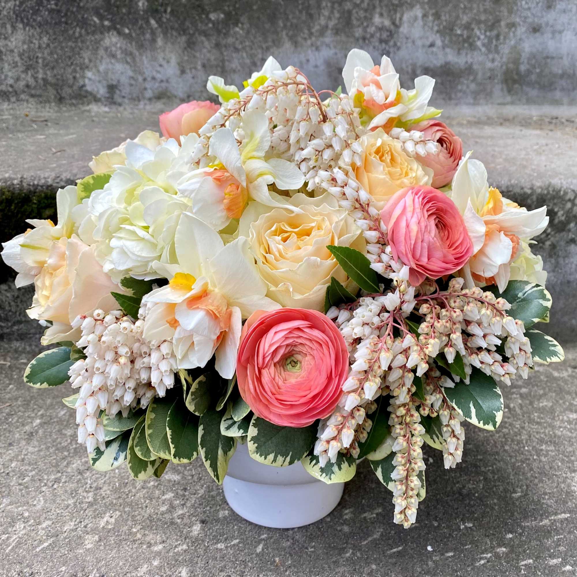 Bouquet of cream, pink, and peach flowers in a white vase