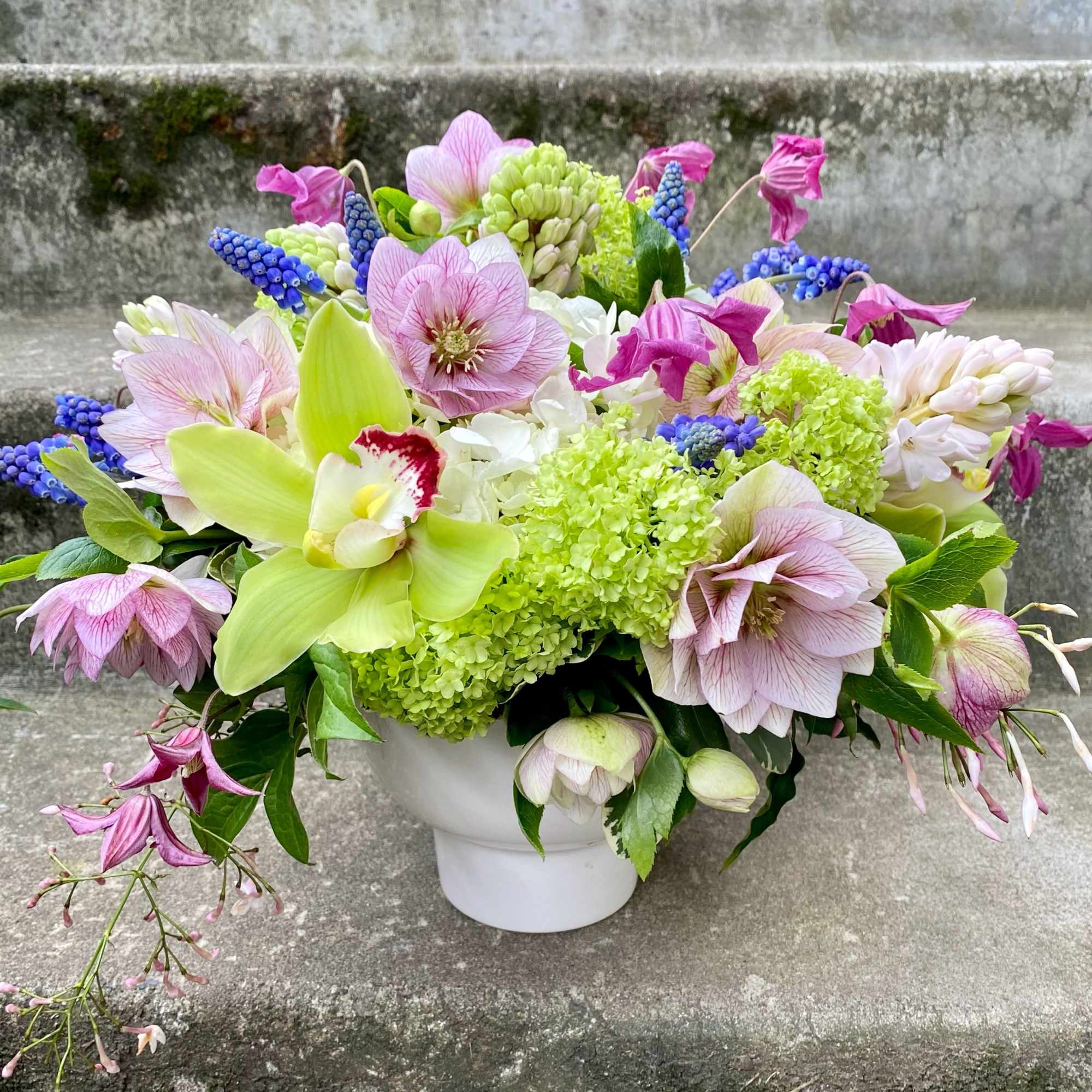 Mixed bouquet of pink and green flowers in a white vase