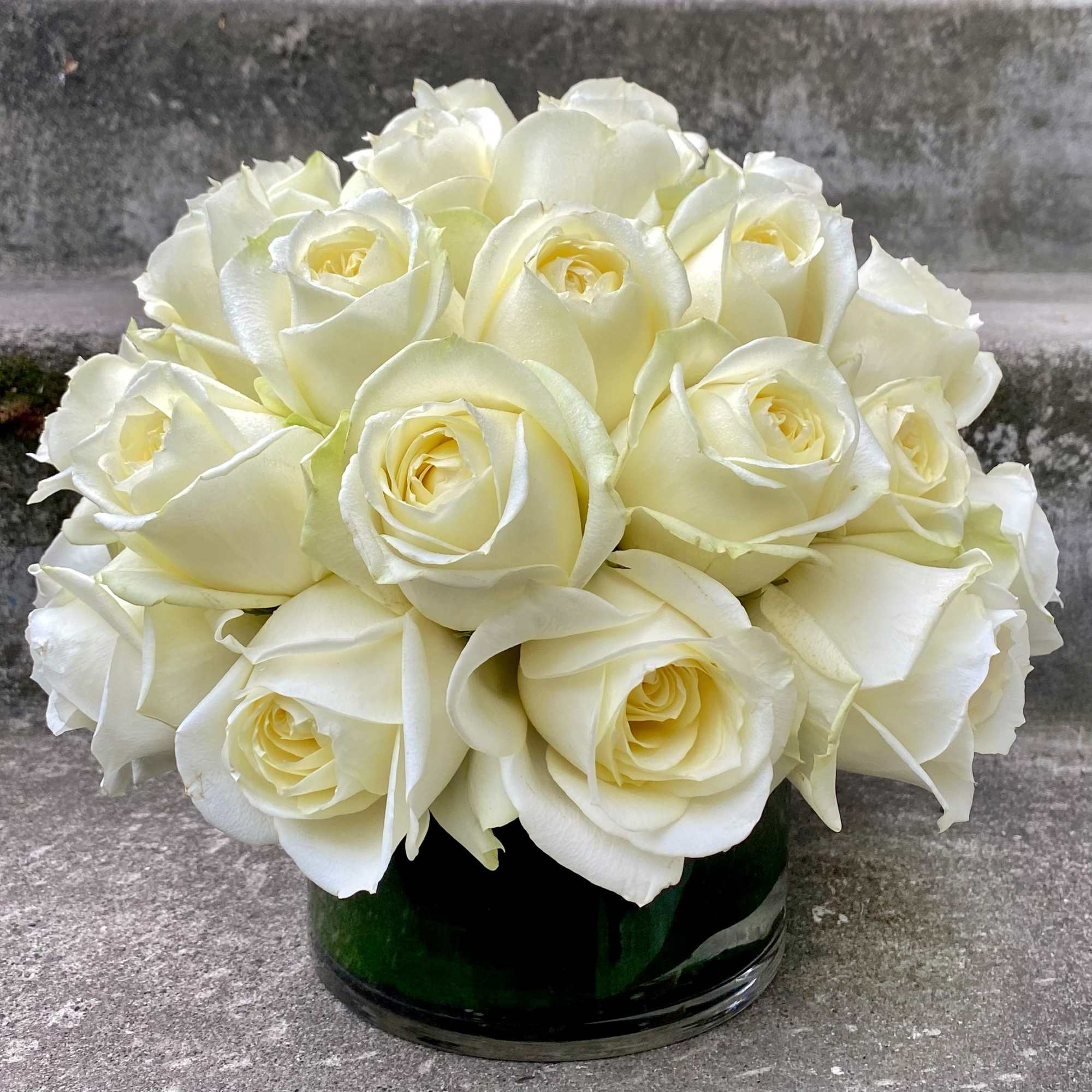 Bouquet of white roses in a dark glass vase