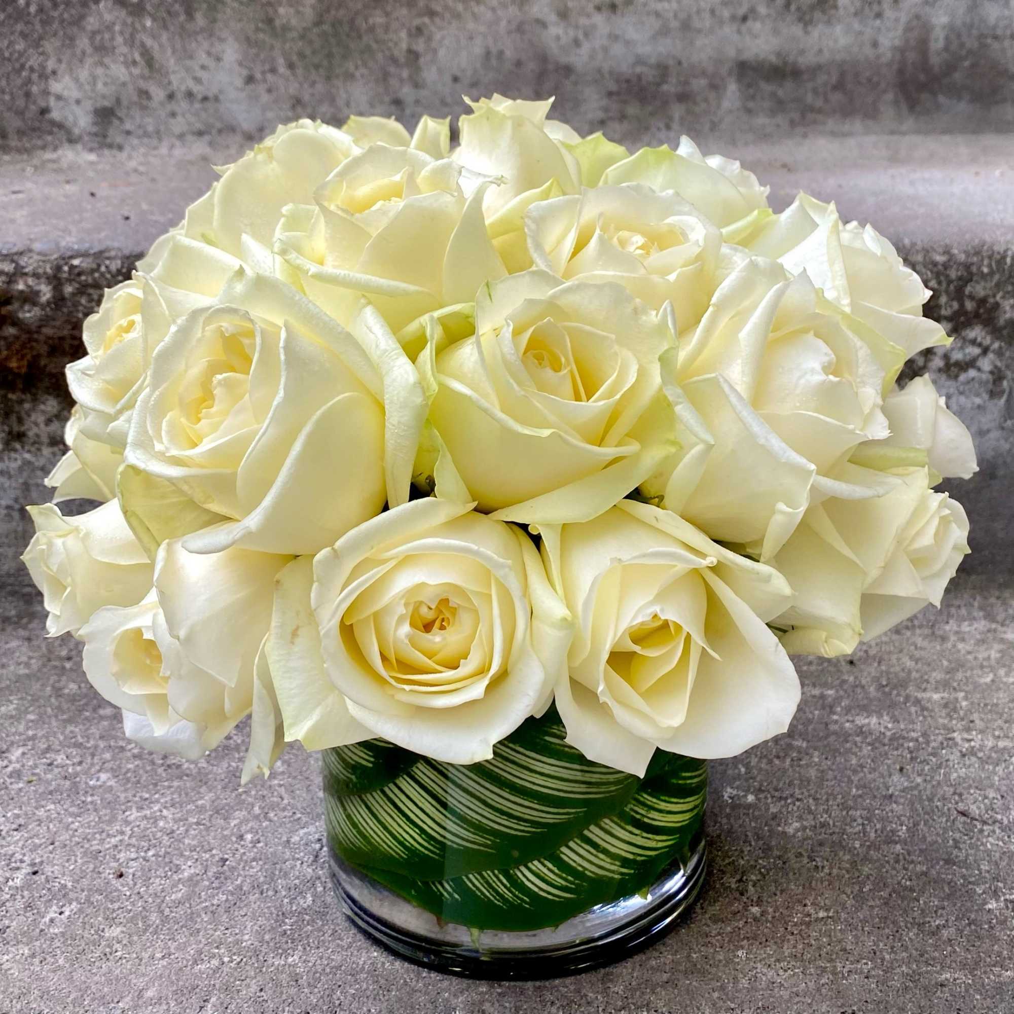 Creamy white rose bouquet in a green glass vase